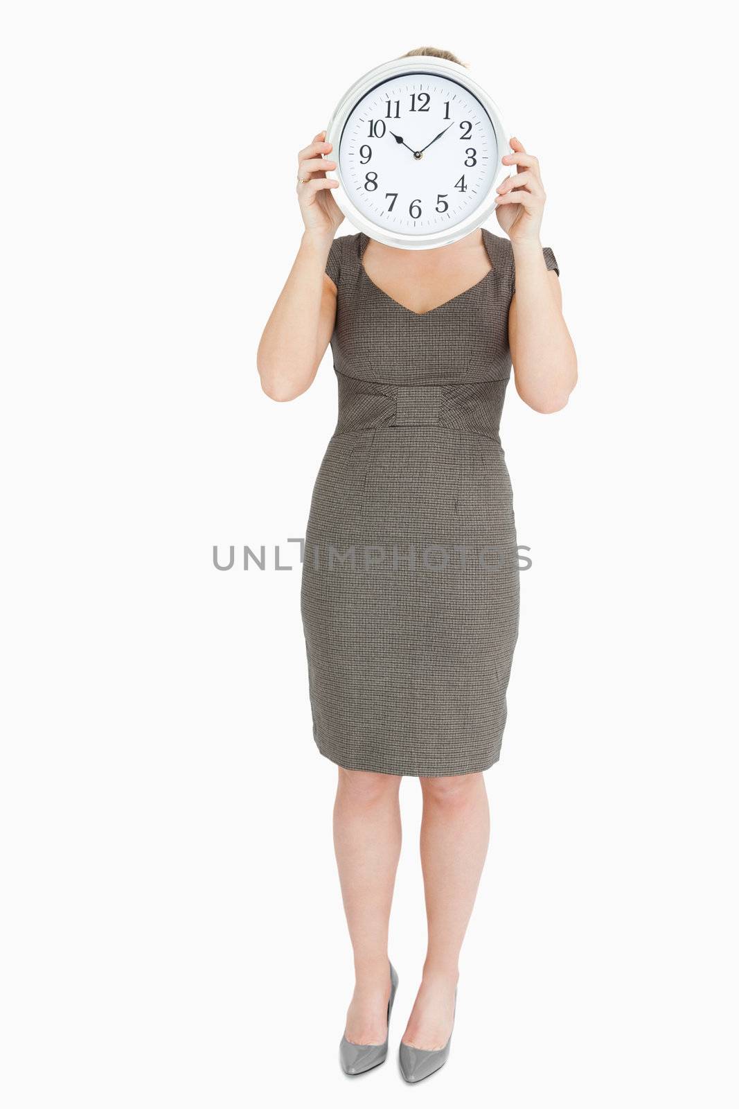 Woman holding a clock hiding her head against white background