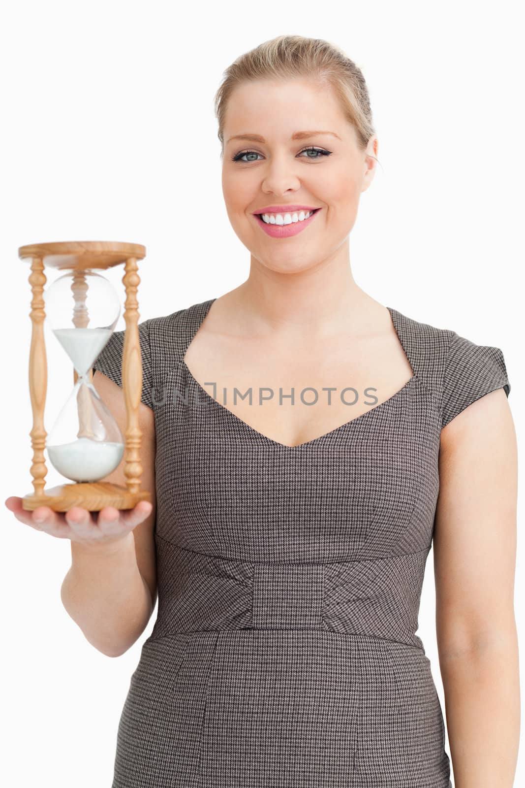 Woman smiling while holding a hourglass against white background