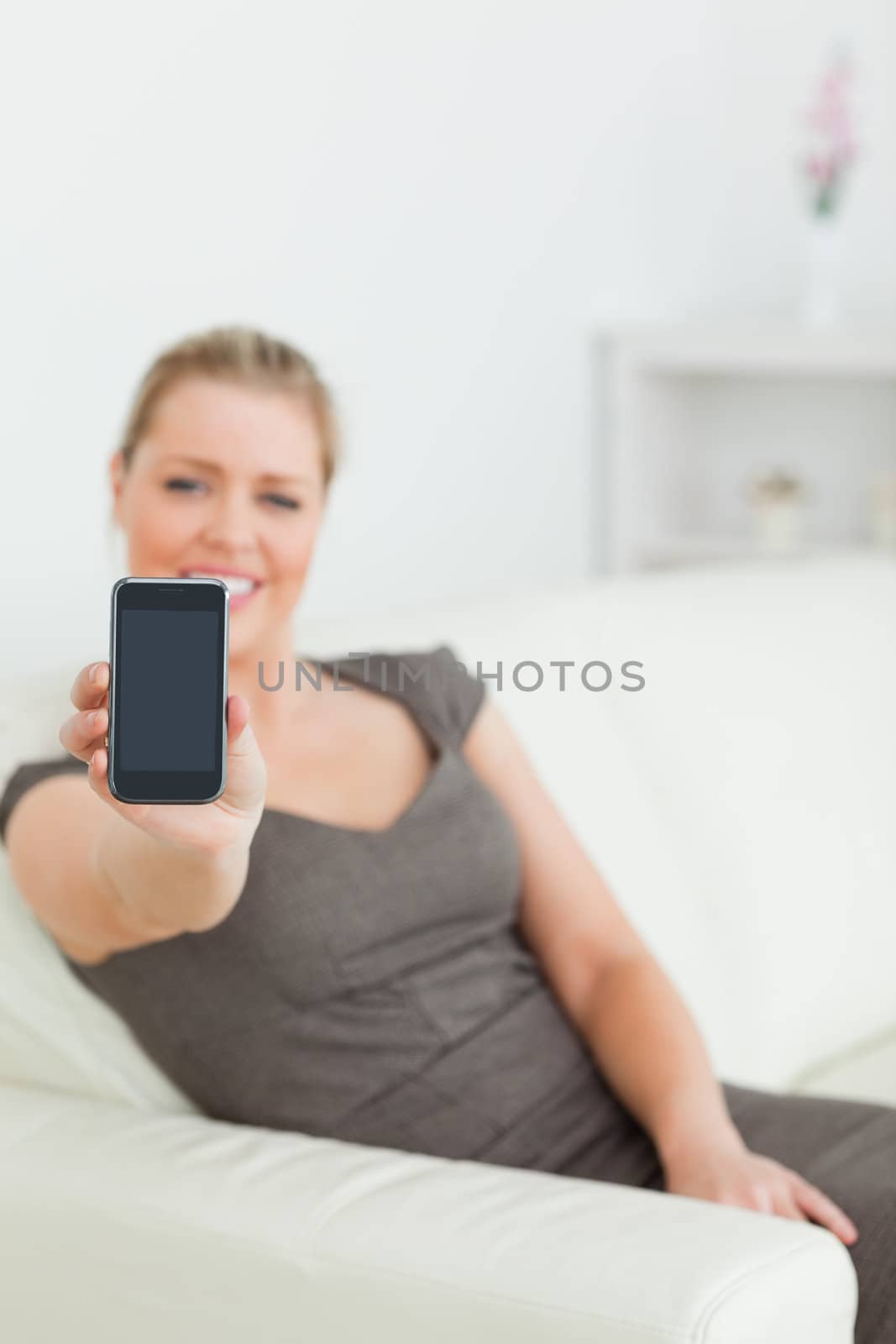 Woman showing a screen of a smartphone sitting on a sofa