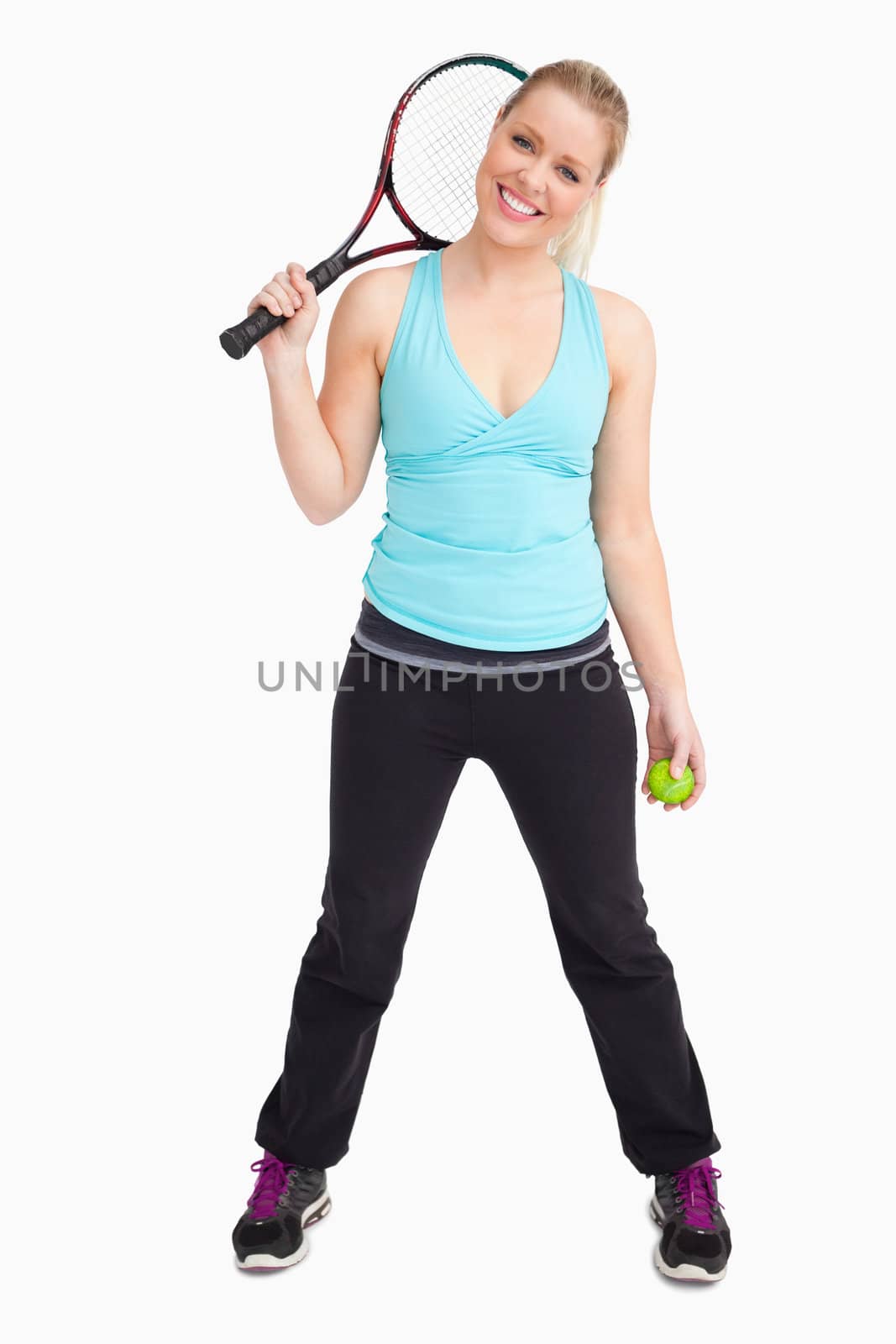 Woman having a ball and tennis racquet againsta white background