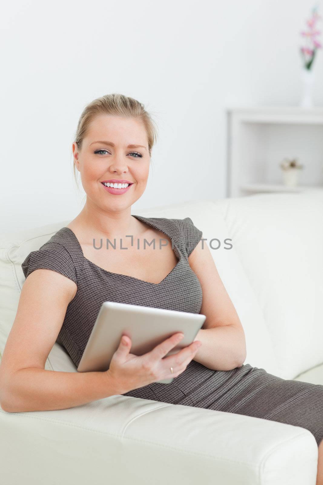 Woman smiling using a tablet pc on a sofa
