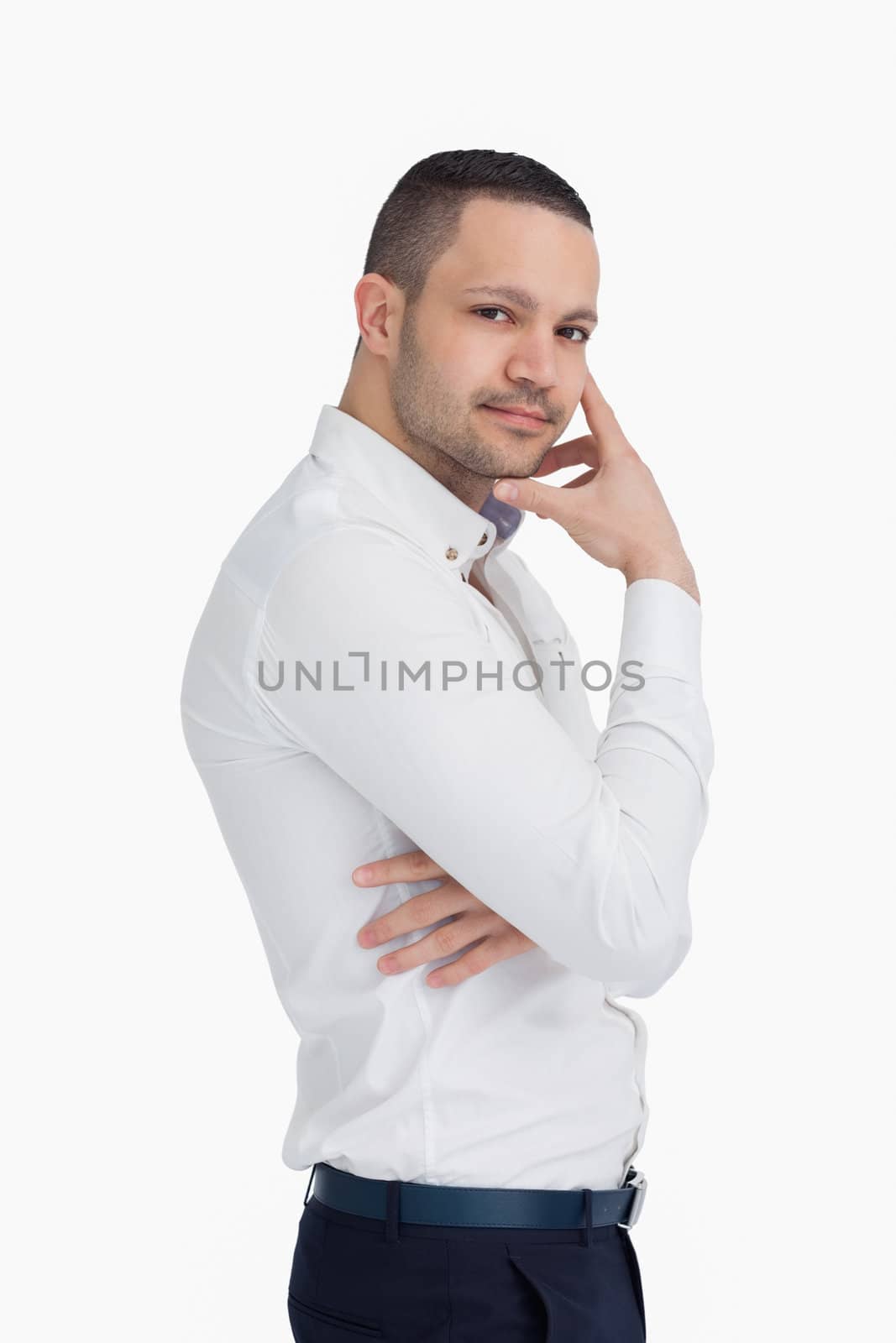 Man standing up while holding his chin with his hand against a white background