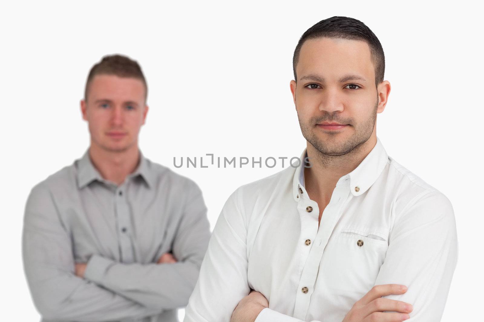Two men standing while crossing their arms against a white background