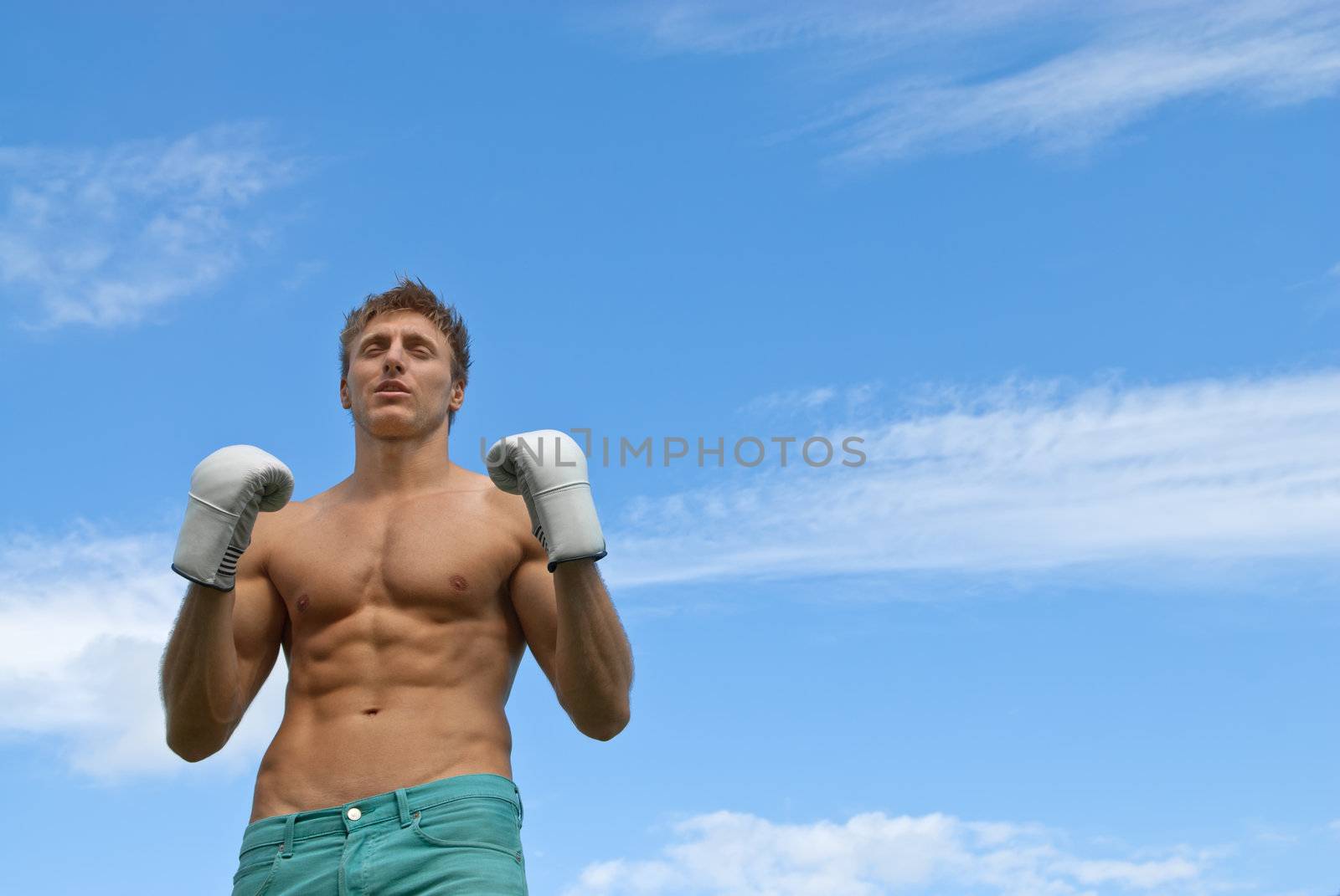 Athletic young man in boxing gloves by anikasalsera