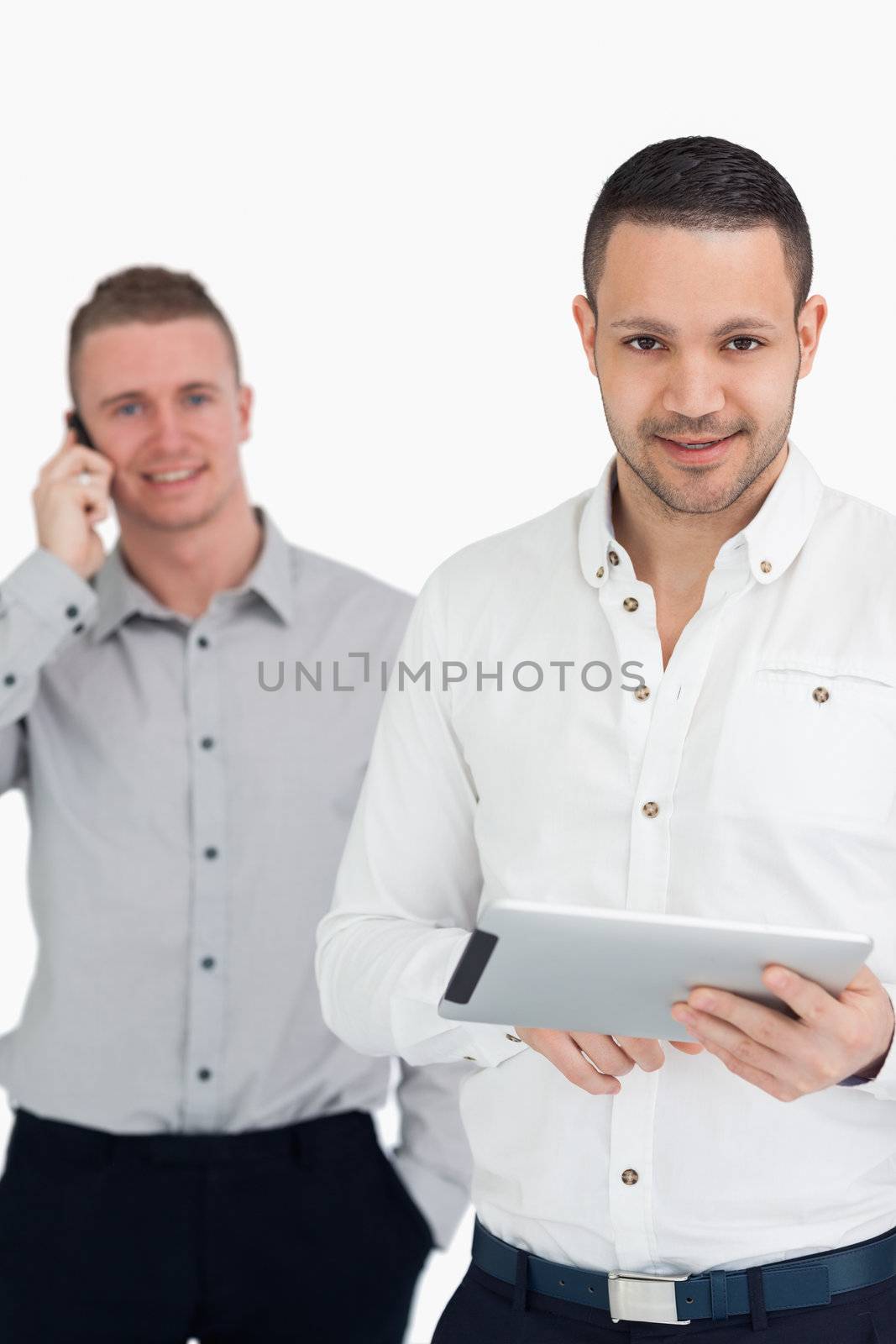 Two smiling men using phone and tablet computer against a white background