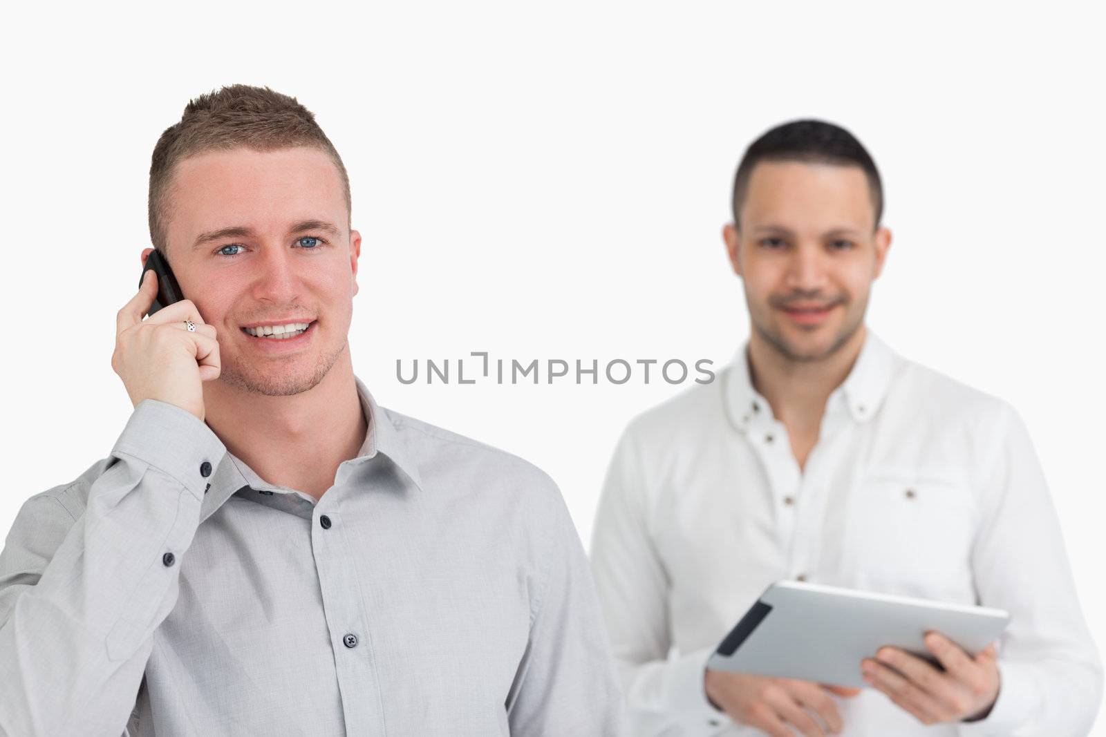 Two men with phone and tablet computer against a white background