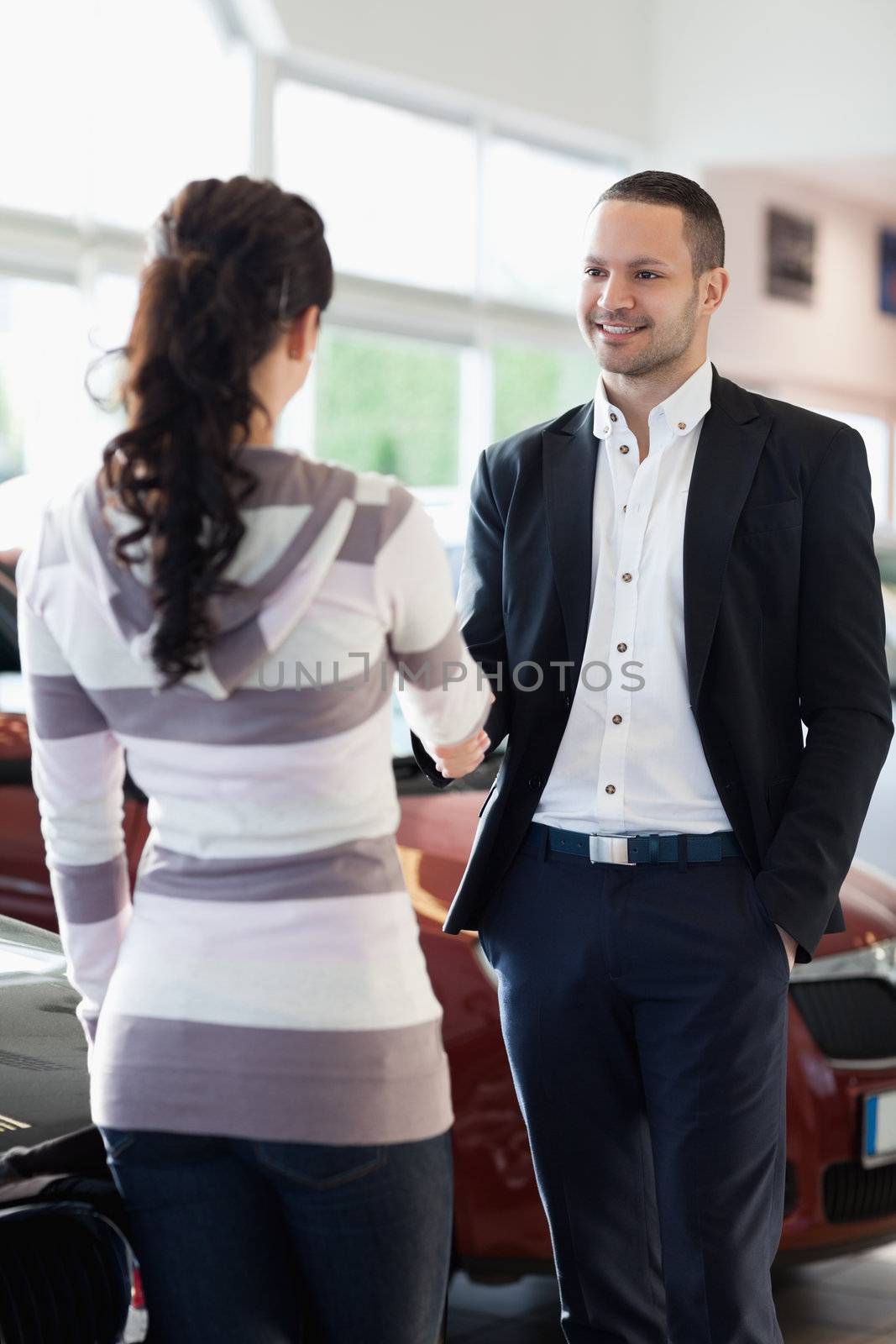 Car dealer shaking hand with a customer in a car shop