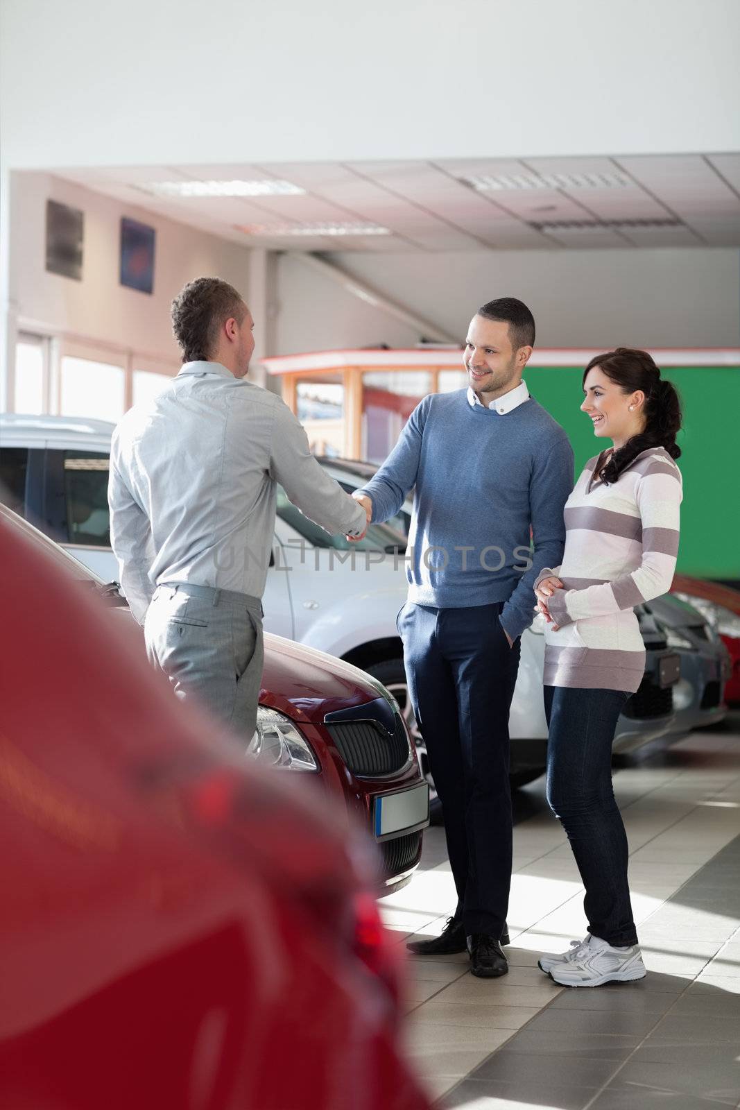 Car dealer shaking hand with a man in a car shop