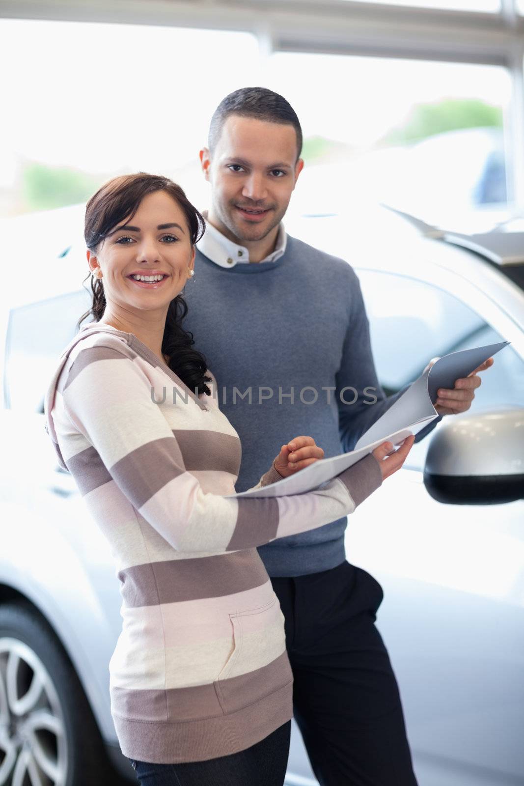 Smiling couple holding a document by Wavebreakmedia