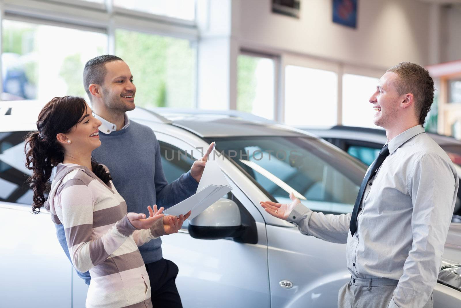 Couple chatting with a salesman in a carshop