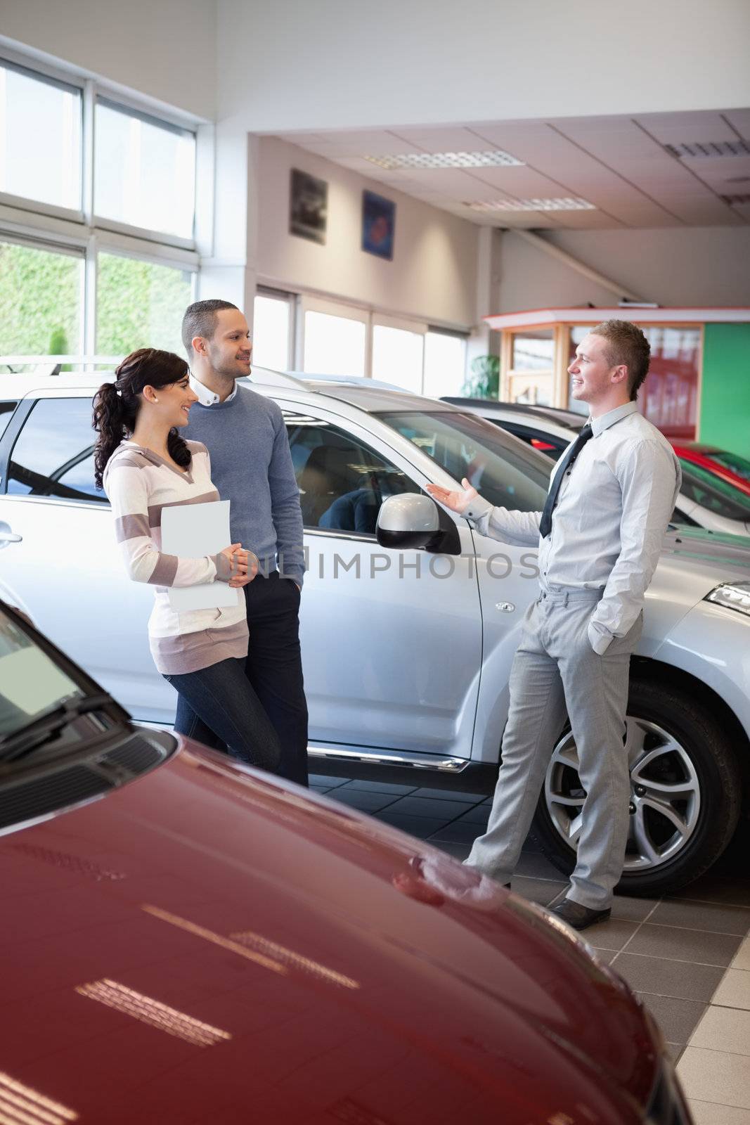 Salesman talking with a couple in a carshop