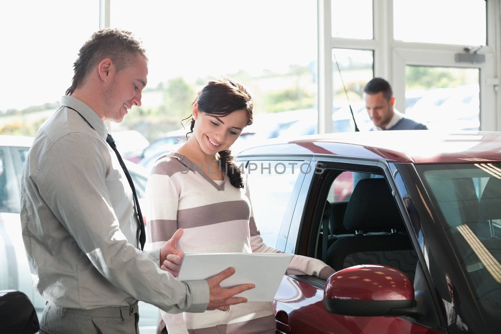 Smiling woman chatting with a car dealer in a car shop