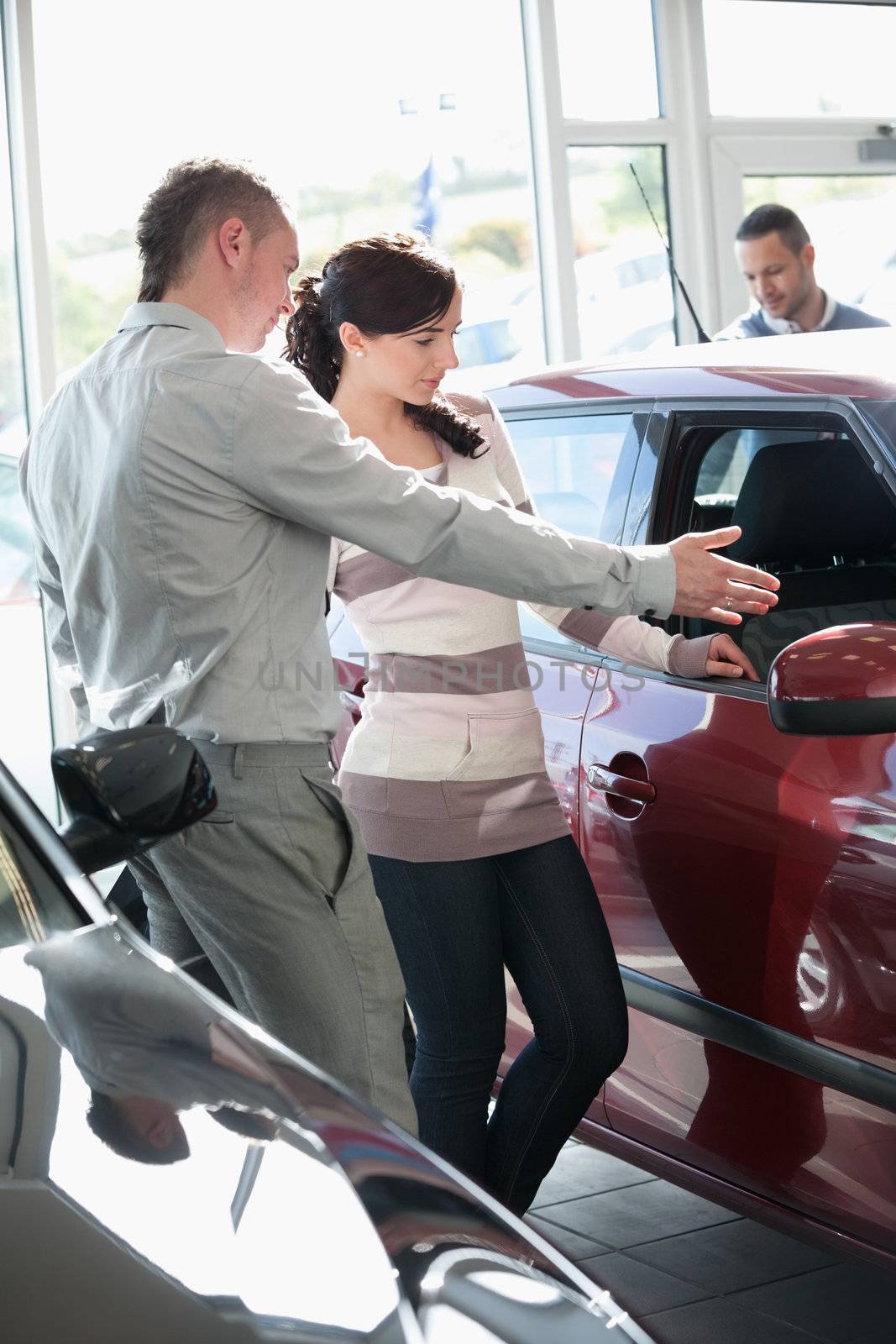 Woman looking at a car interior being pointed by a salesman