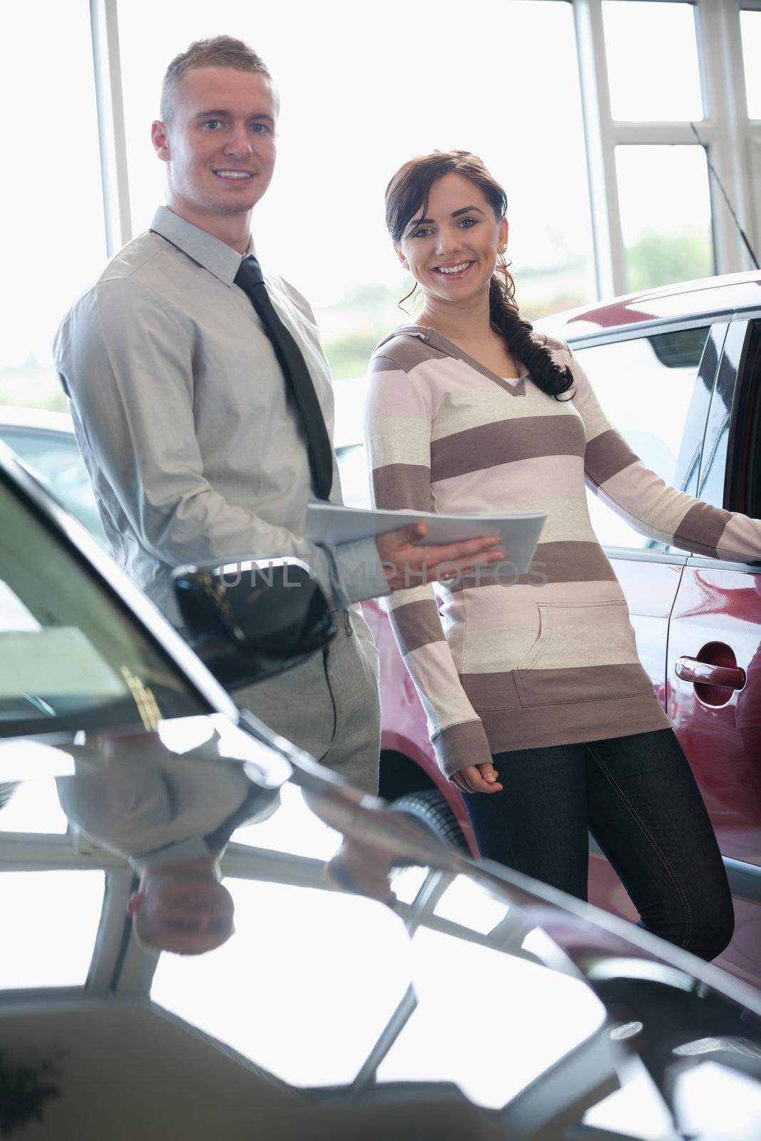 Salesman and a woman standing next to a car by Wavebreakmedia