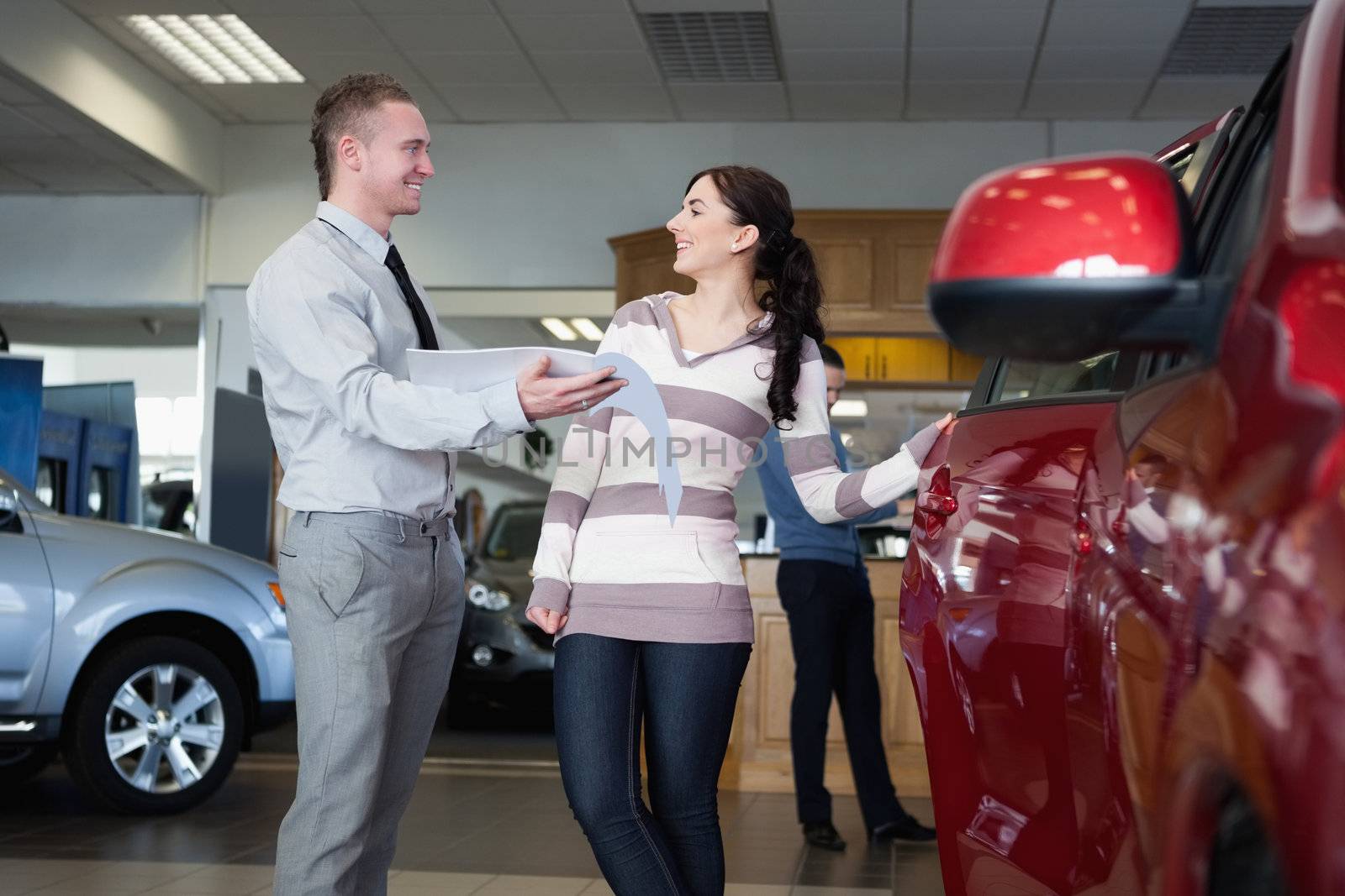 Smiling salesman talking with a woman in a car shop