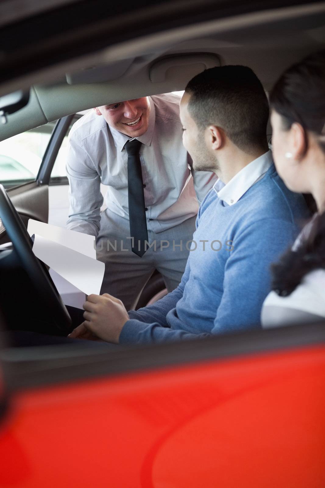 Salesman giving car keys to a couple in a car in a car shop