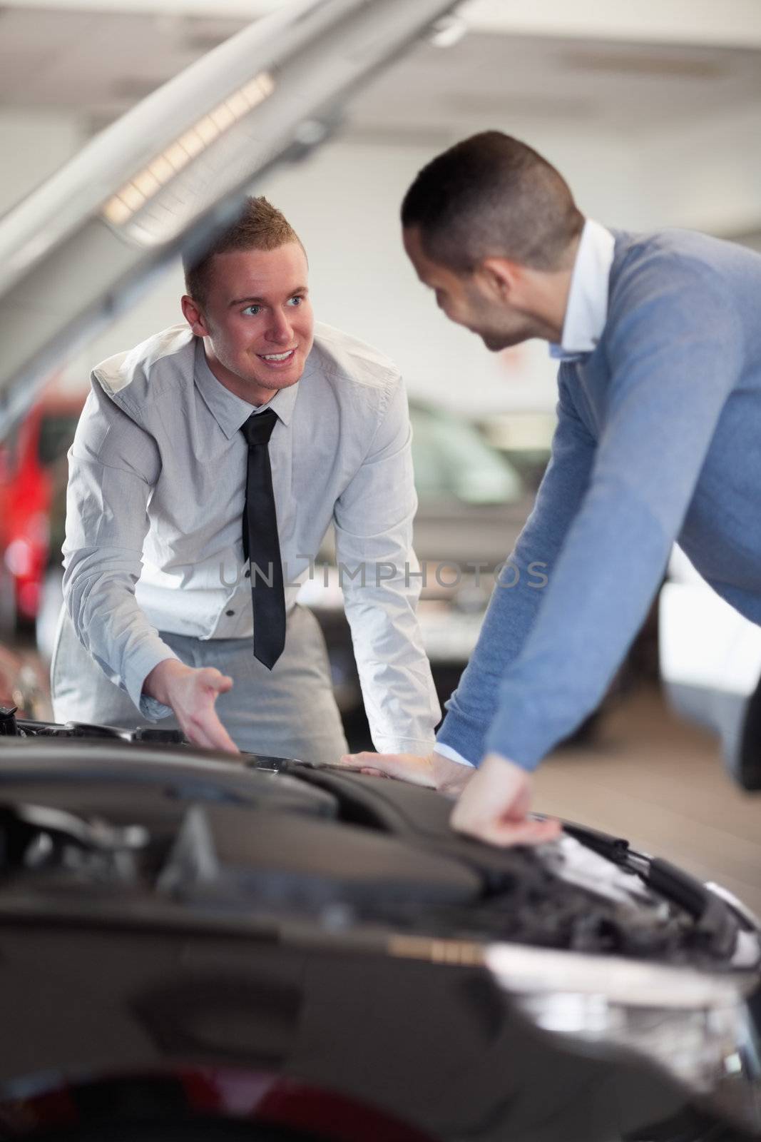 Two men looking at a car engine in a car shop