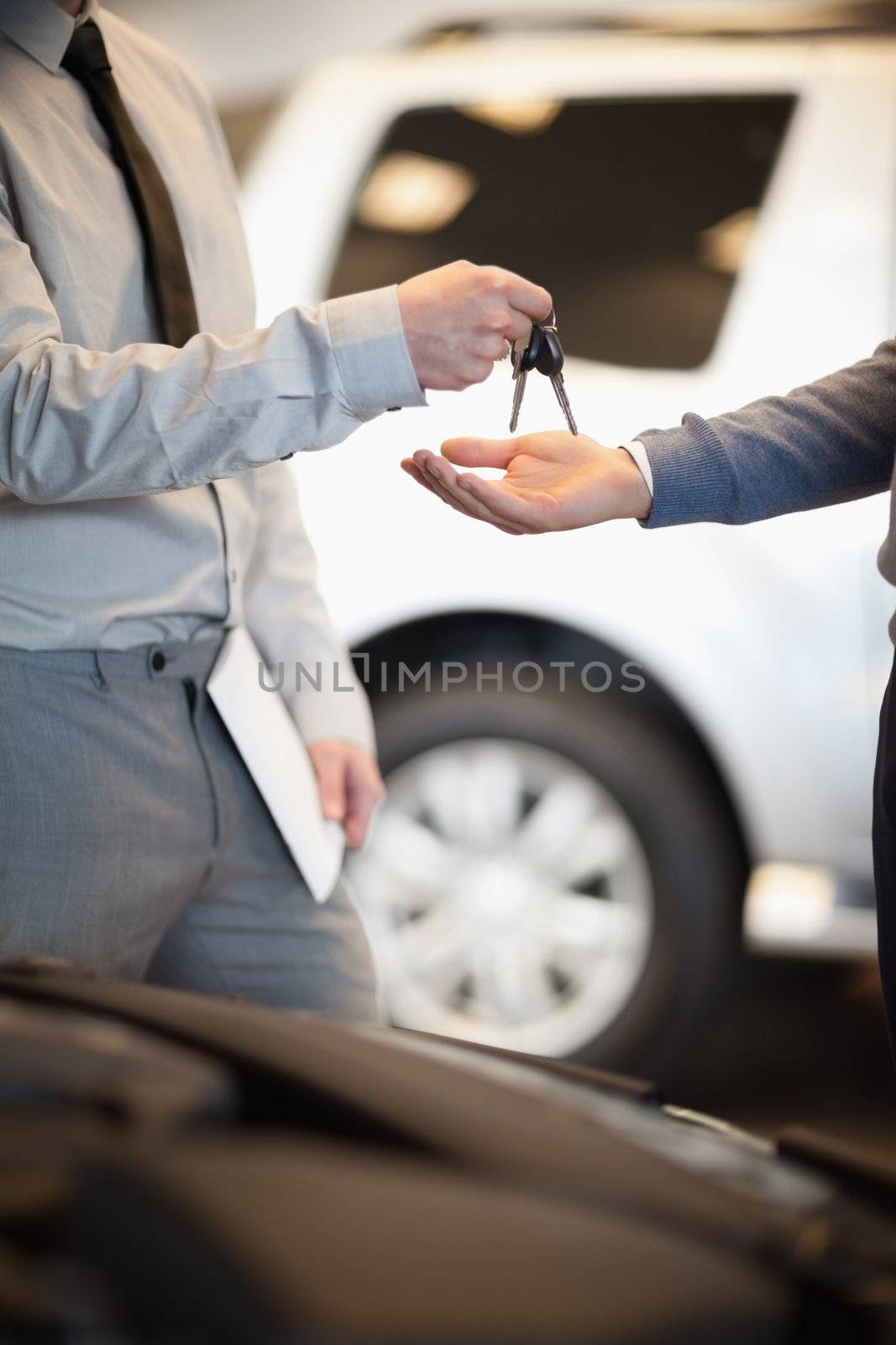 Salesman handing keys to a customer in a car shop