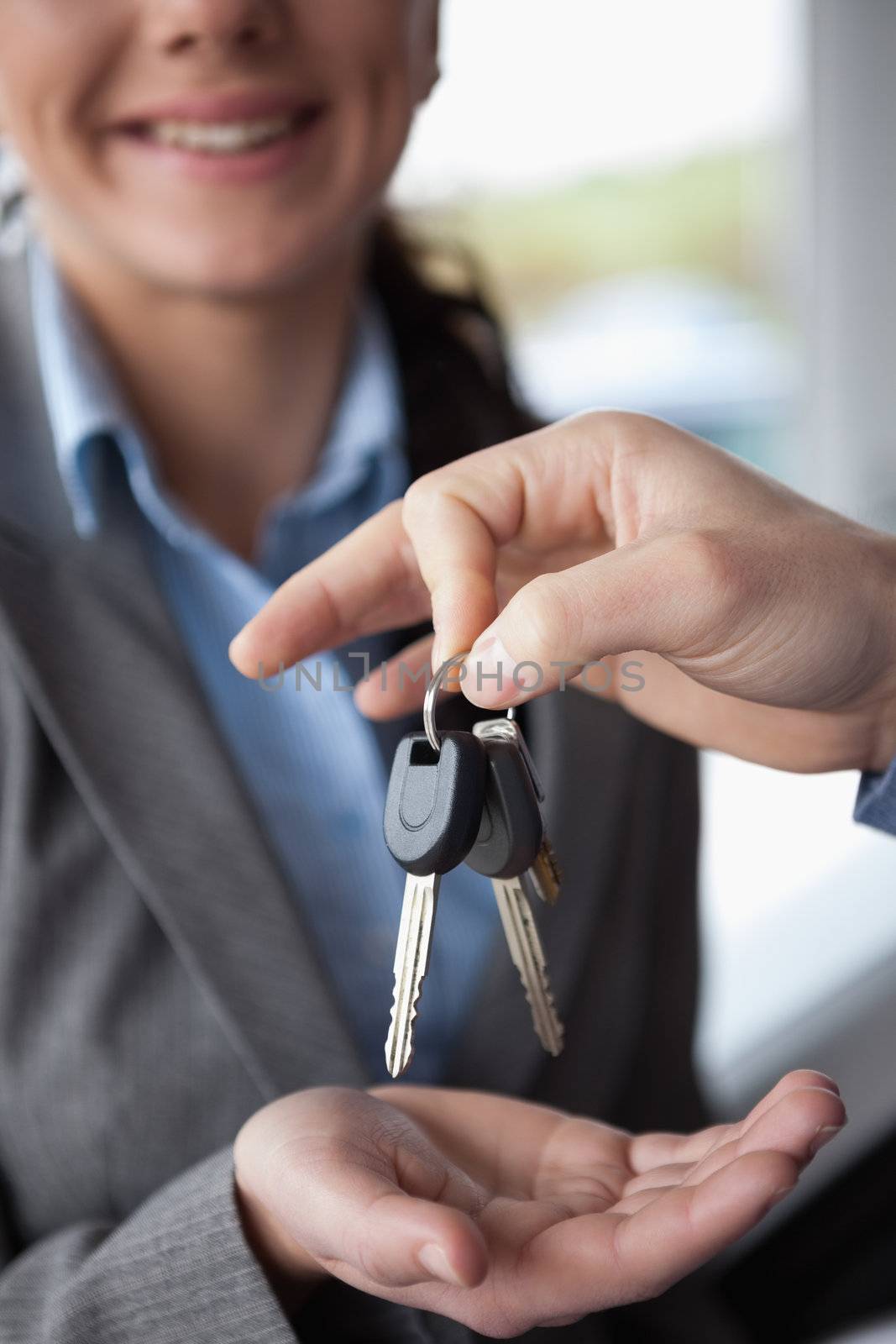 Hand holding keys over the hand of a woman in a car shop