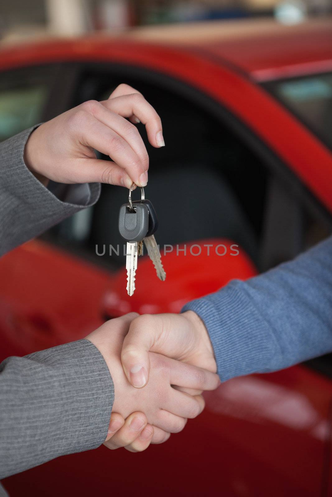 People shaking hands while holding keys in a car shop
