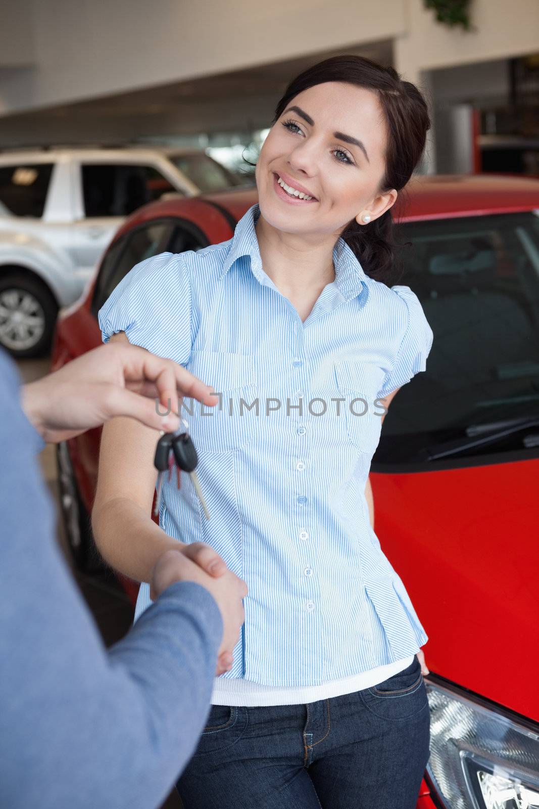 Smiling woman shaking the hand of a man in a car shop