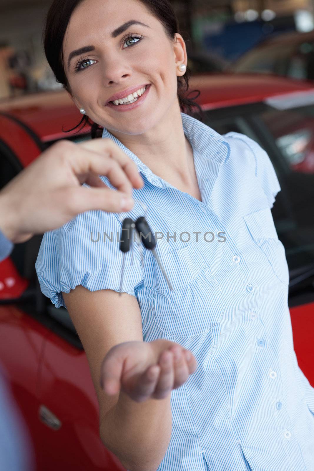 Woman smiles while receiving a car key in a car shop