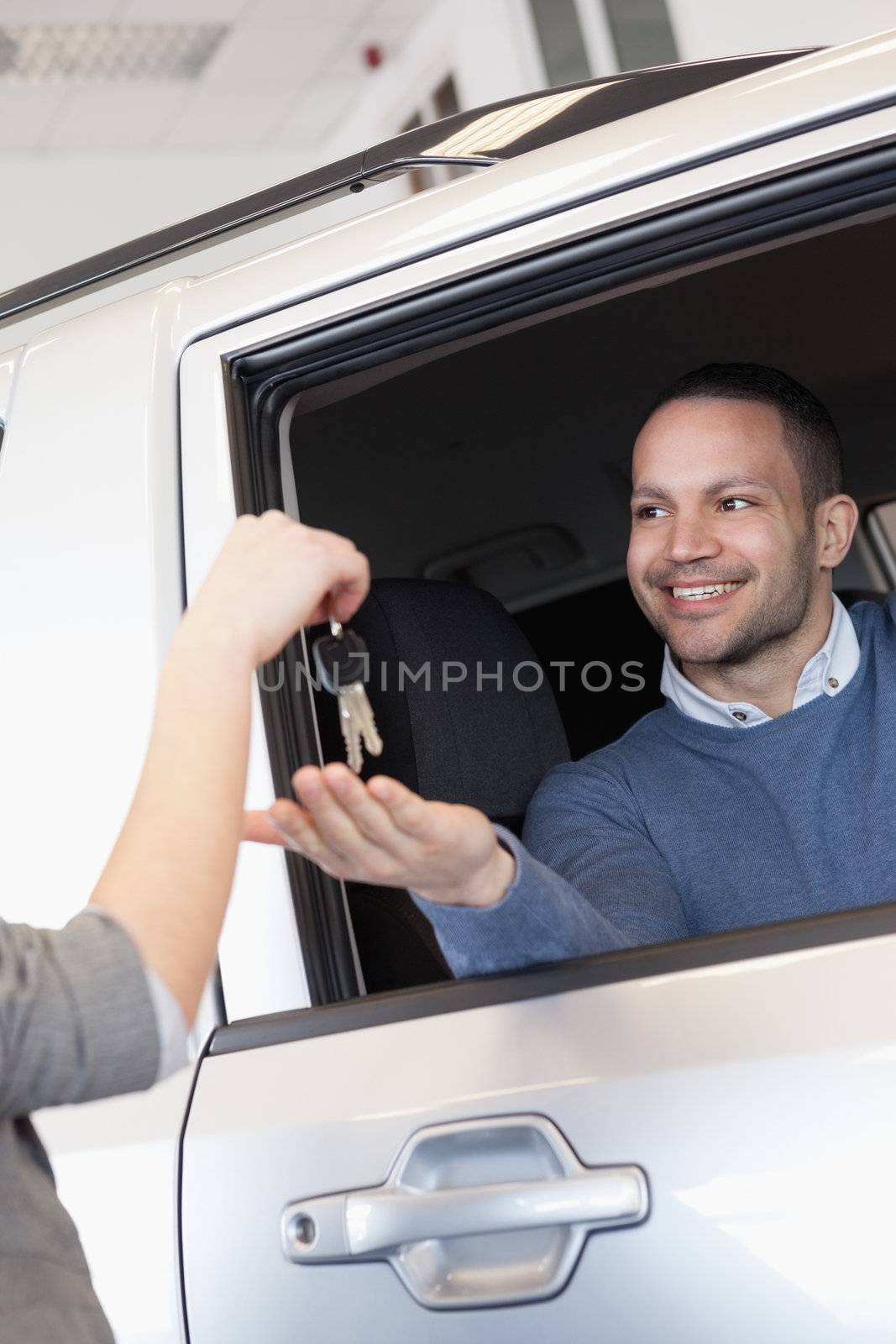 Smiling man in a car receiving a car key in a car shop