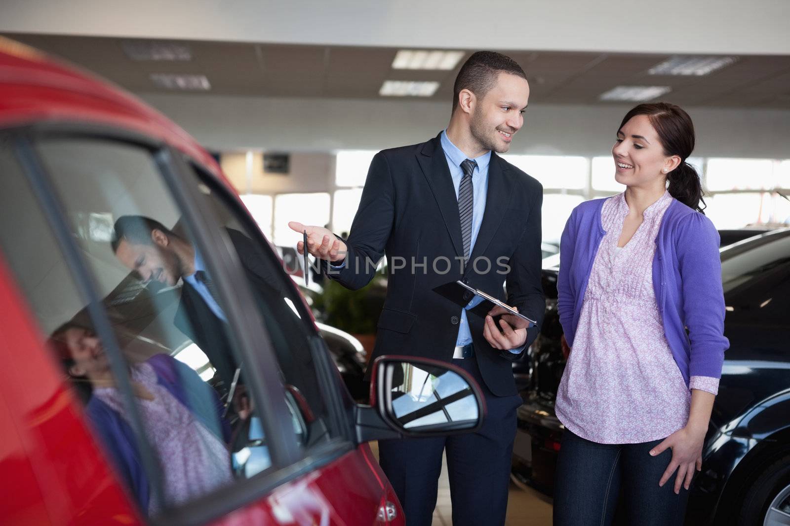 Salesman showing a car to a woman in a car shop