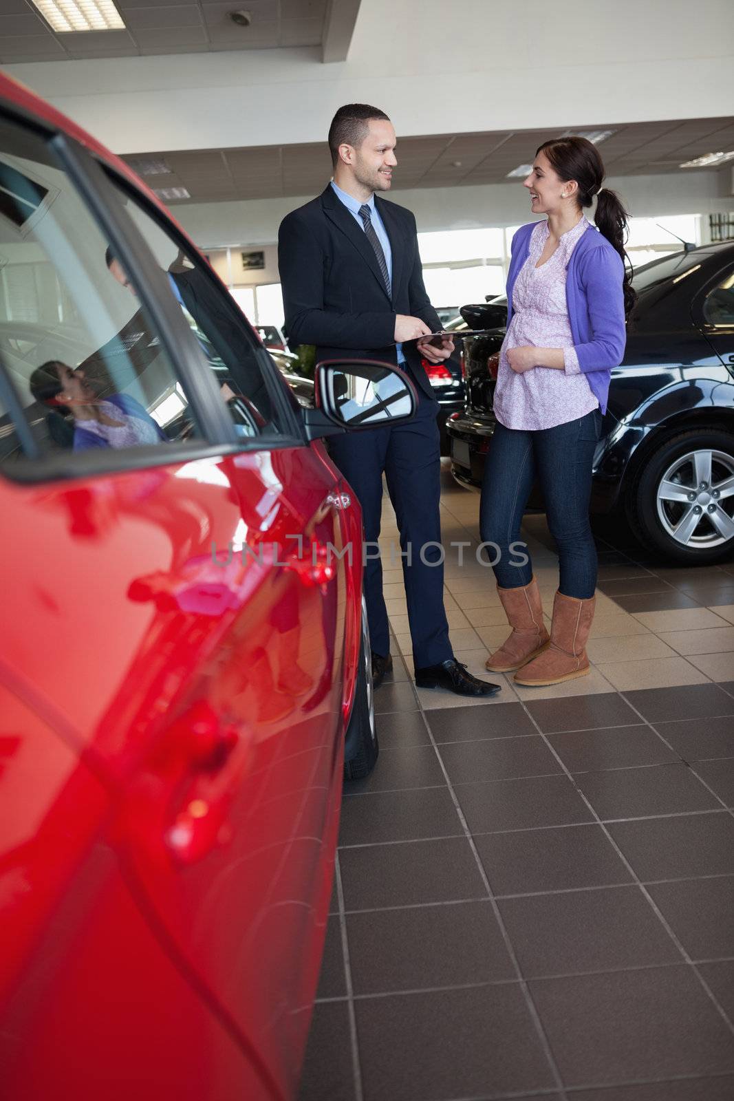 Woman smiles as she talks with a salesman in a car shop