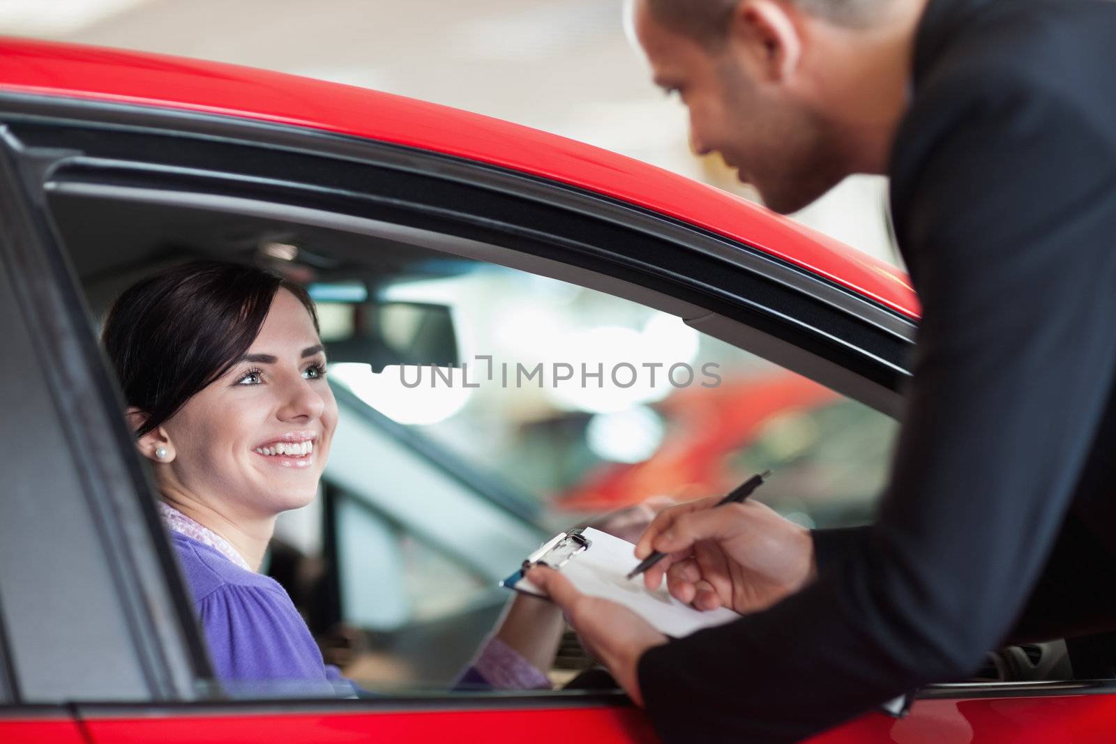 Woman in a car talking with a salesman in a car shop