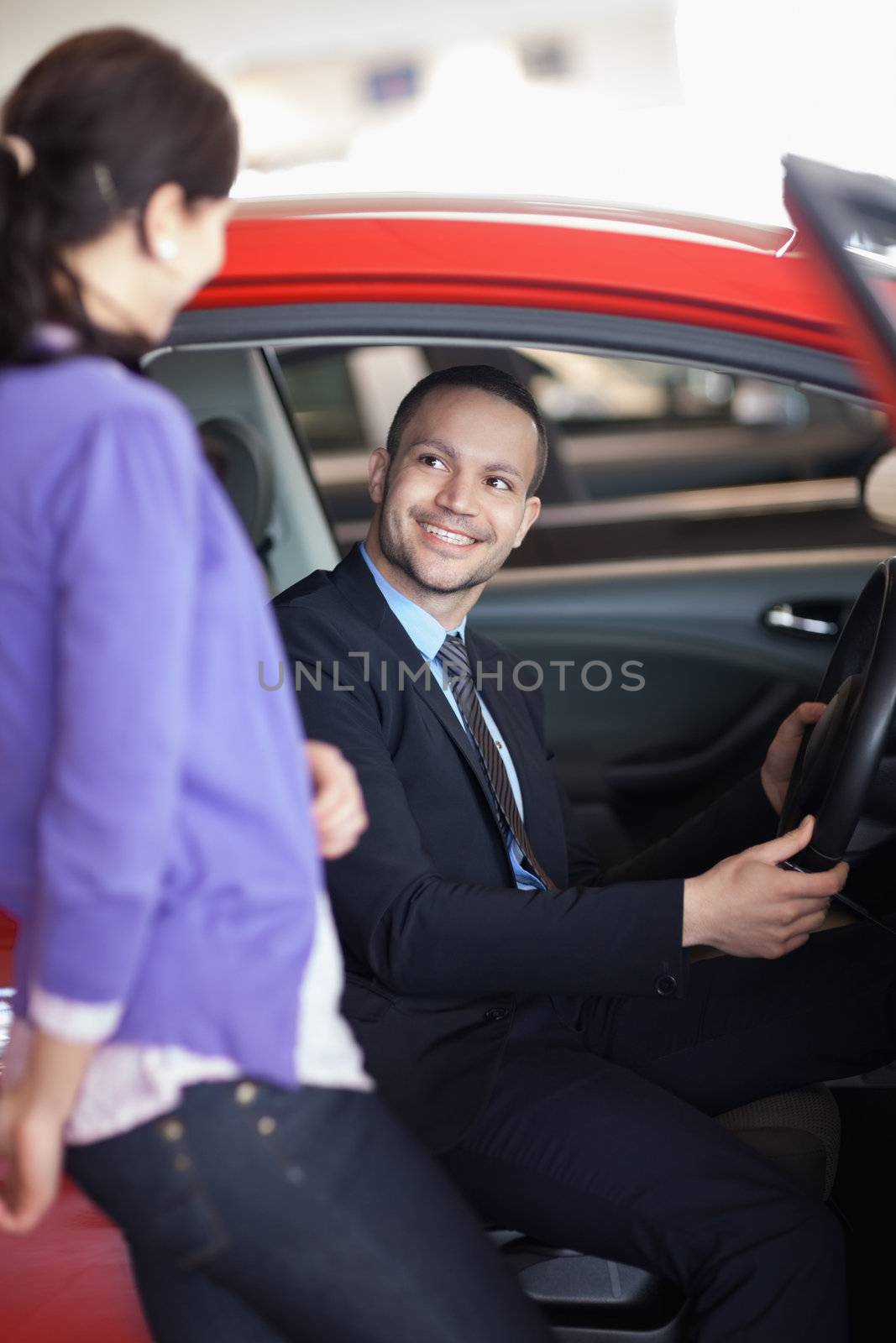 Man sitting in a car while talking to a woman in a car shop