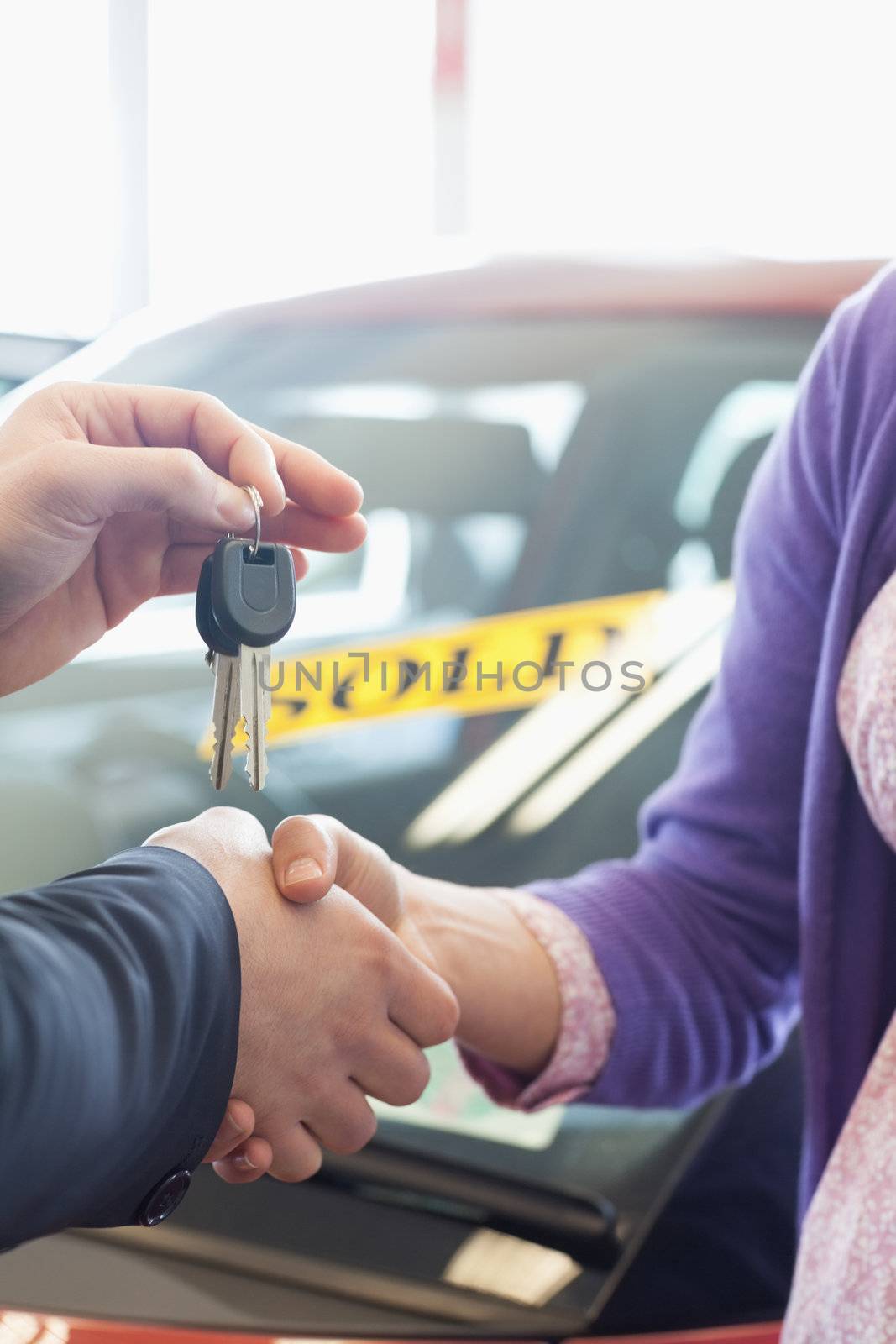 Woman shaking the hand of a man in a car dealership
