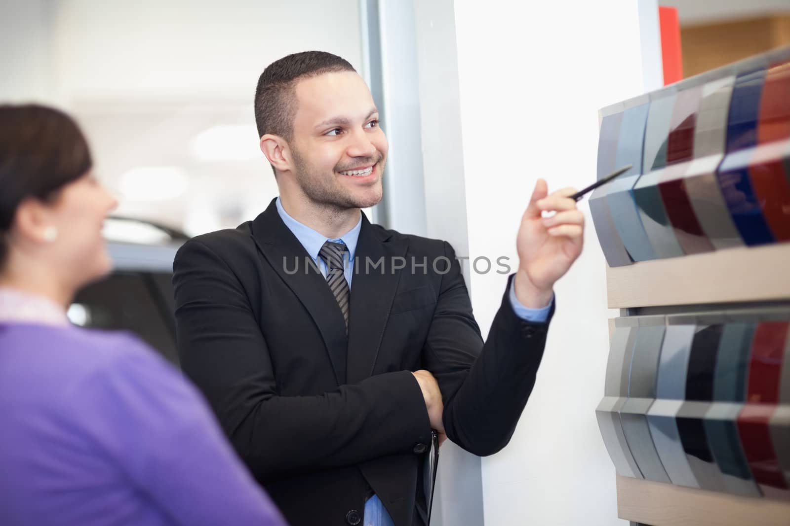 Smiling salesman pointing at a color palette with a woman