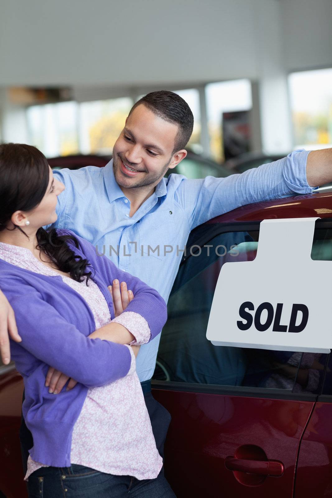 Couple hugging and looking at each other in a car dealership