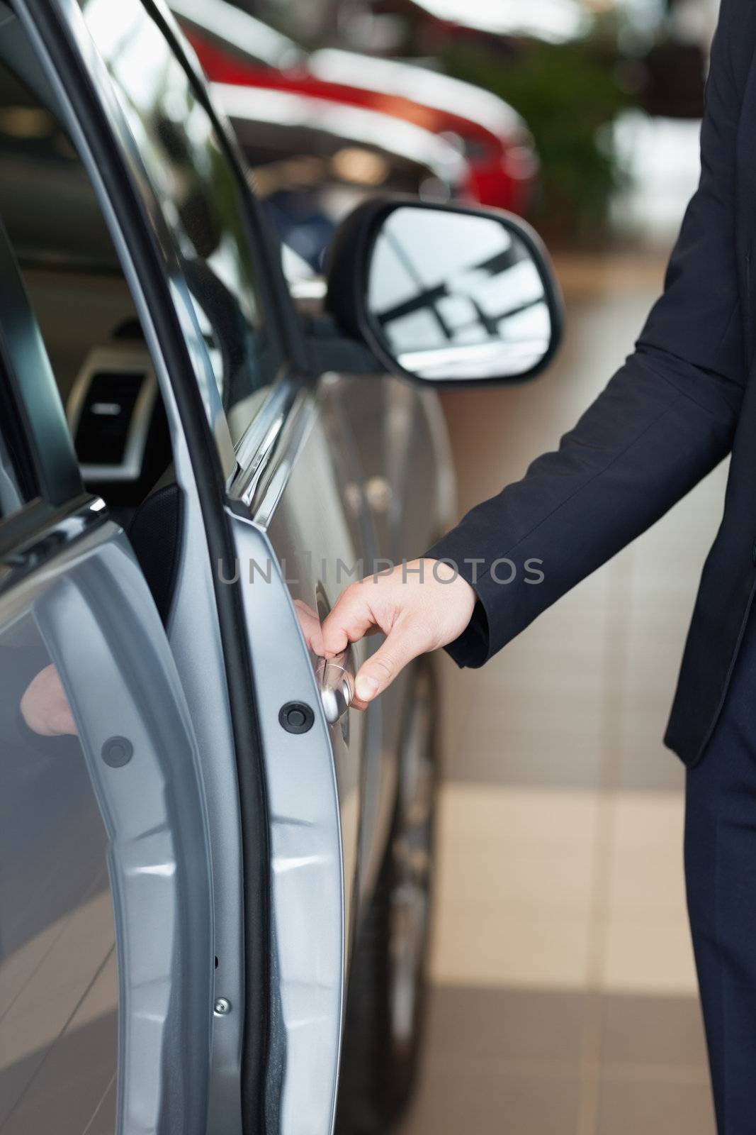 Man holding an half open door in a car dealership