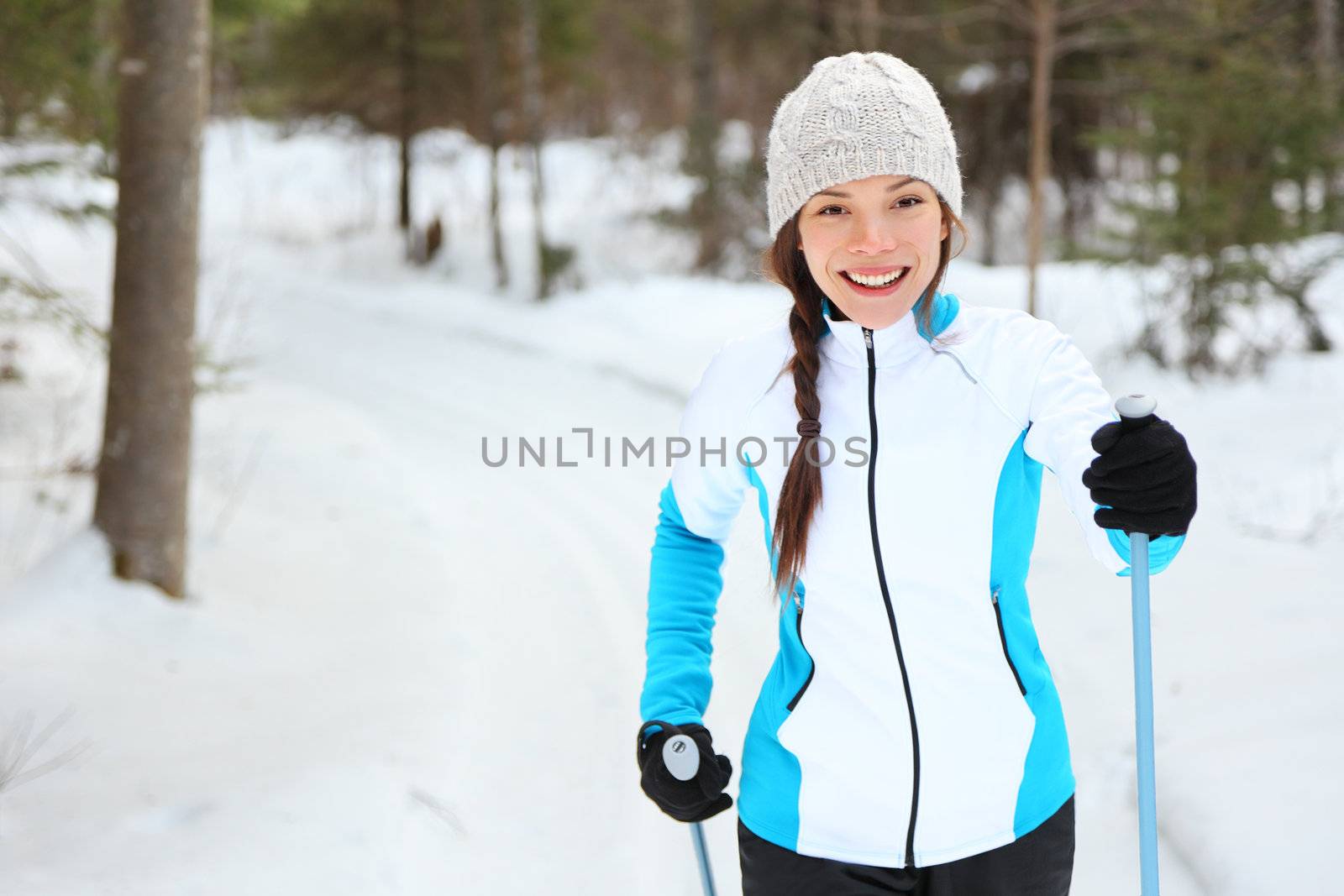Cross-country skiing woman doing classic nordic cross country skiing in trail tracks in snow covered forest in Quebec, Canada