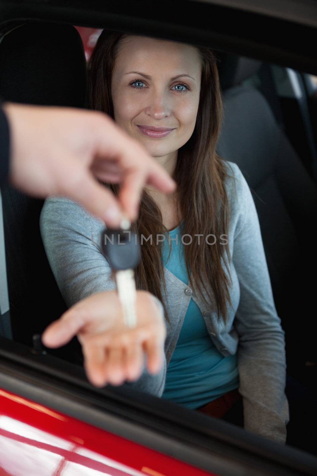 Businessman holding car keys by his fingertips in a dealership