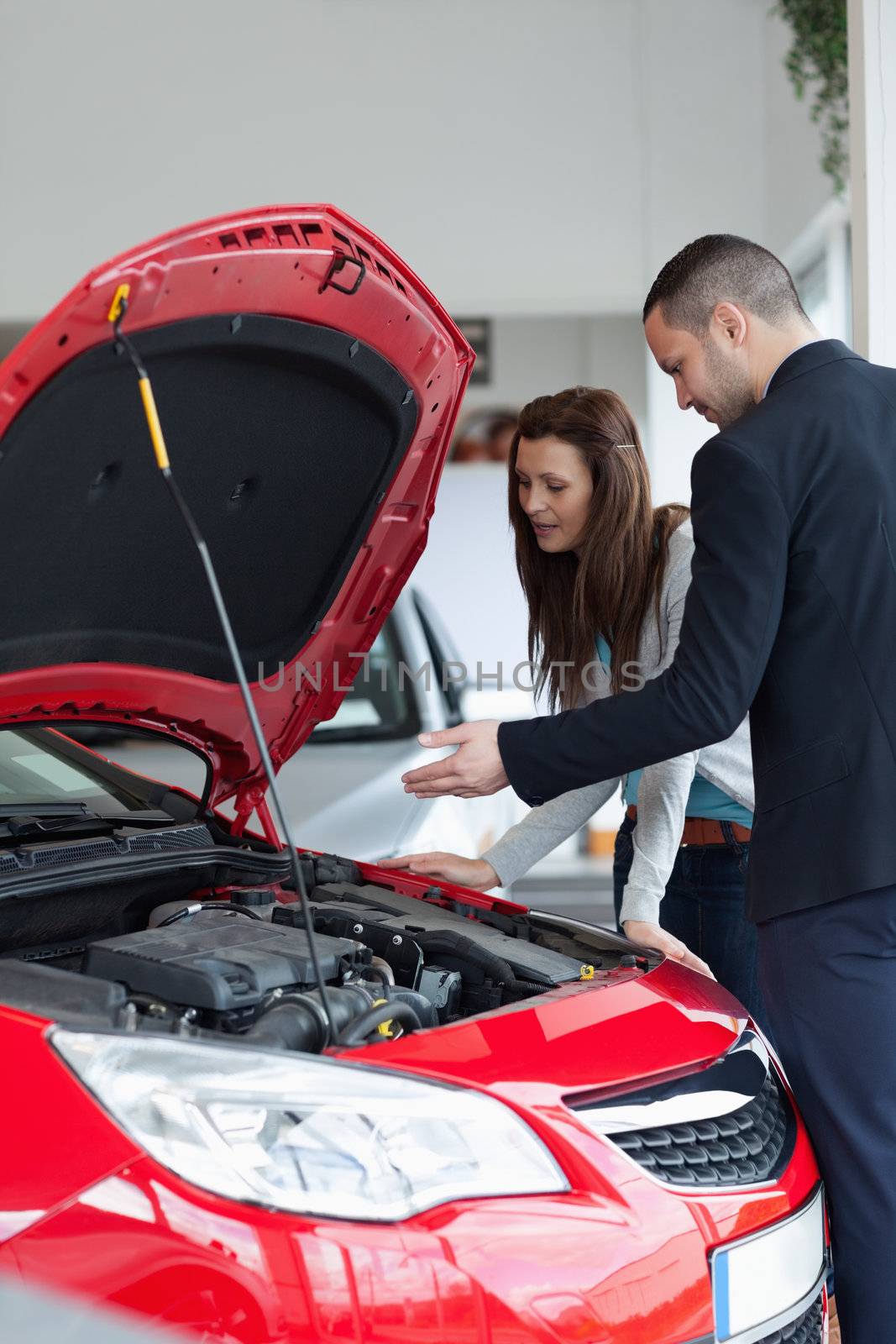 Salesman showing the car engine in a garage