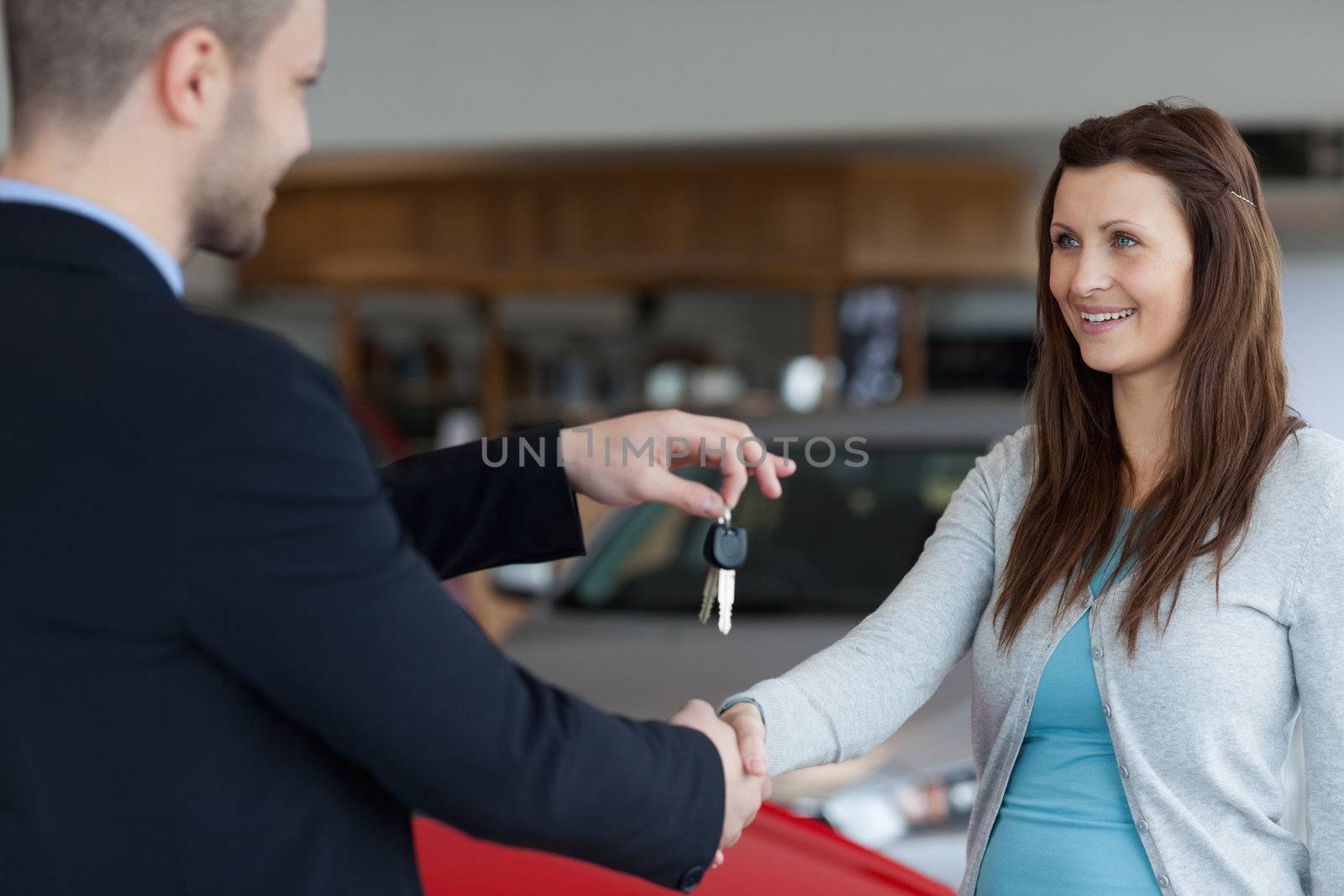 Man giving car keys while shaking hand of a woman in a garage