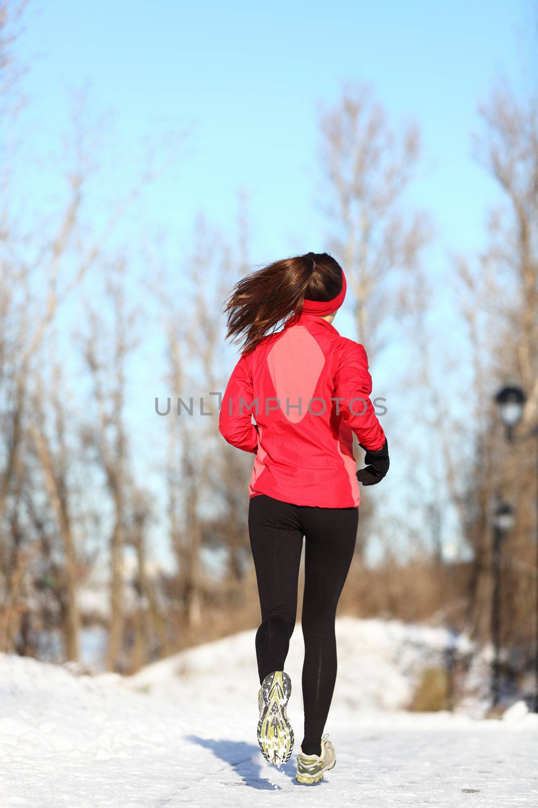 Winter running woman jogging in snow. Female runner in full body. Active lifestyle and wellness concept with young woman fitness model.