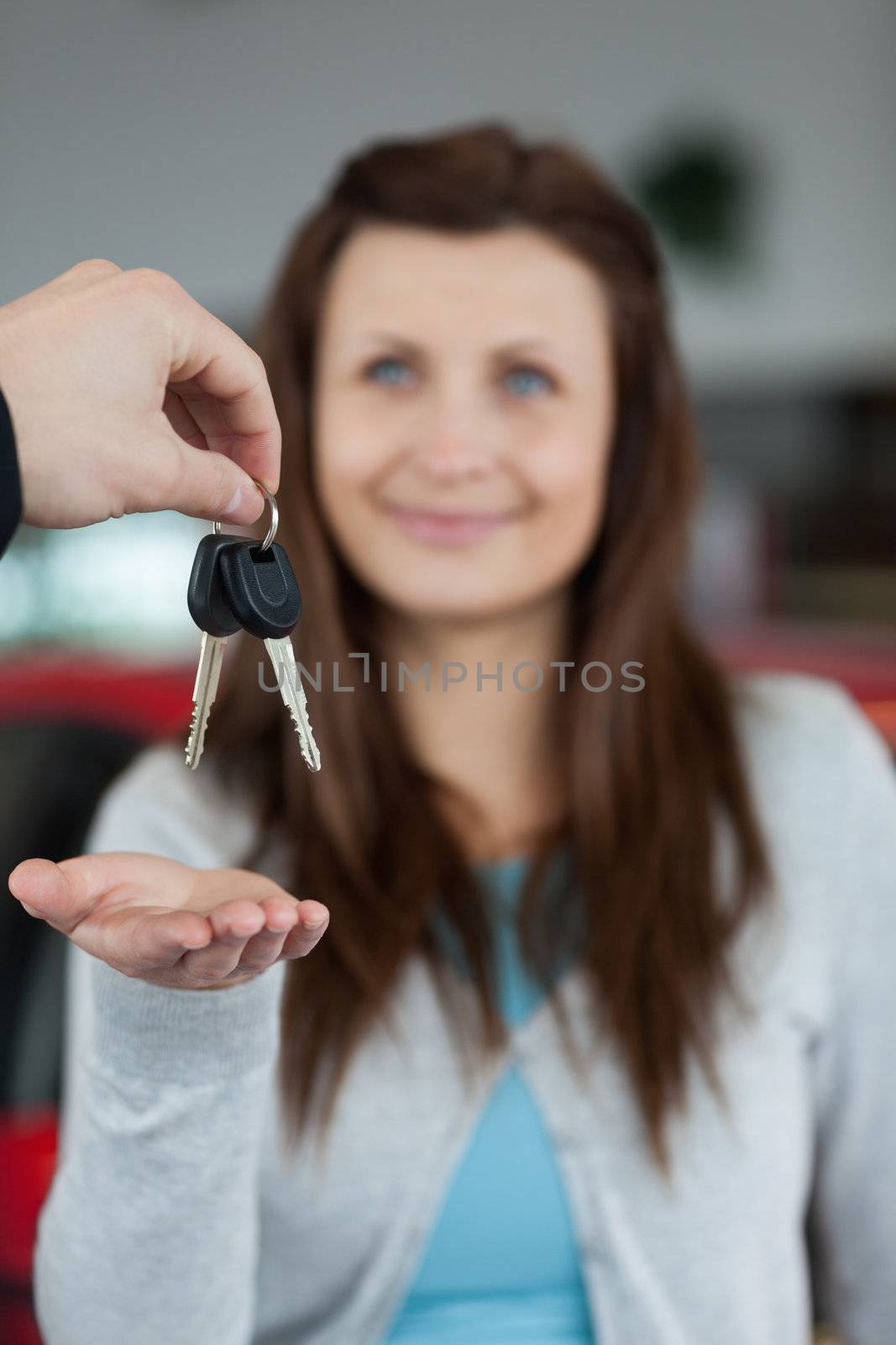 Happy brunette receiving car keys in a garage
