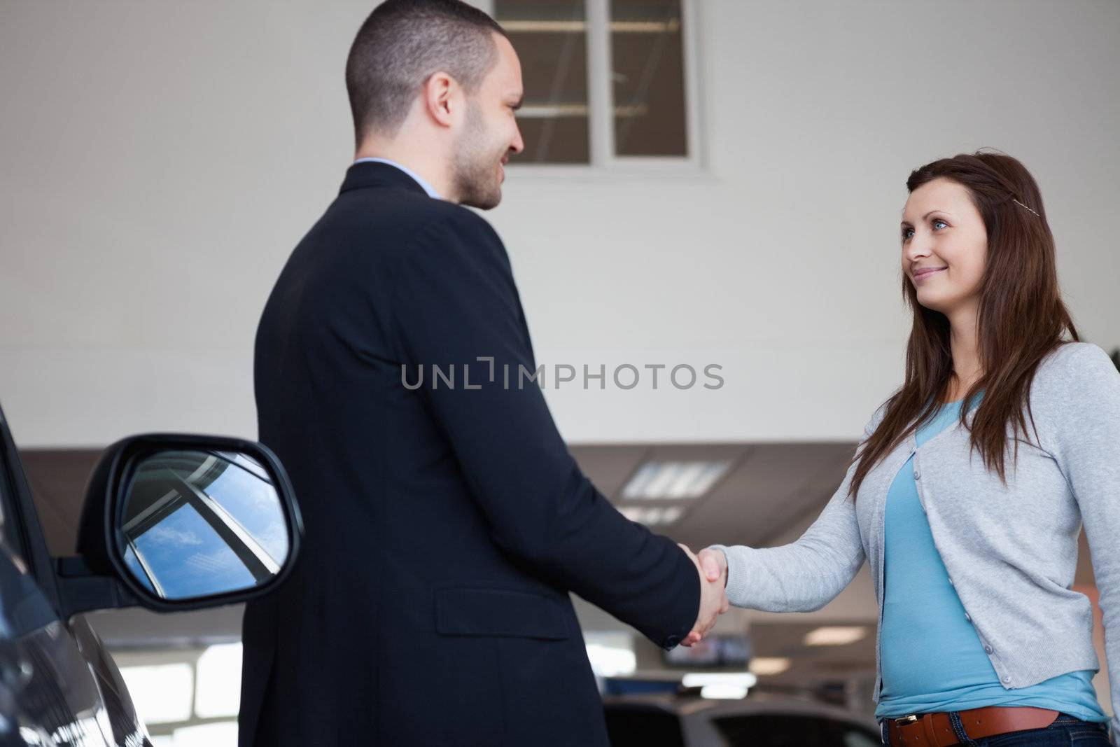 Salesman shaking hand of a client in a garage