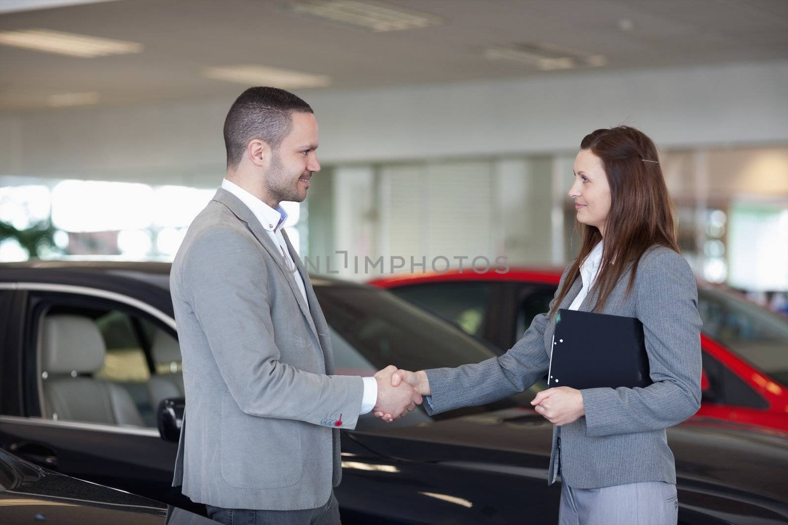 Businesswoman shaking hand of a man in a dealership