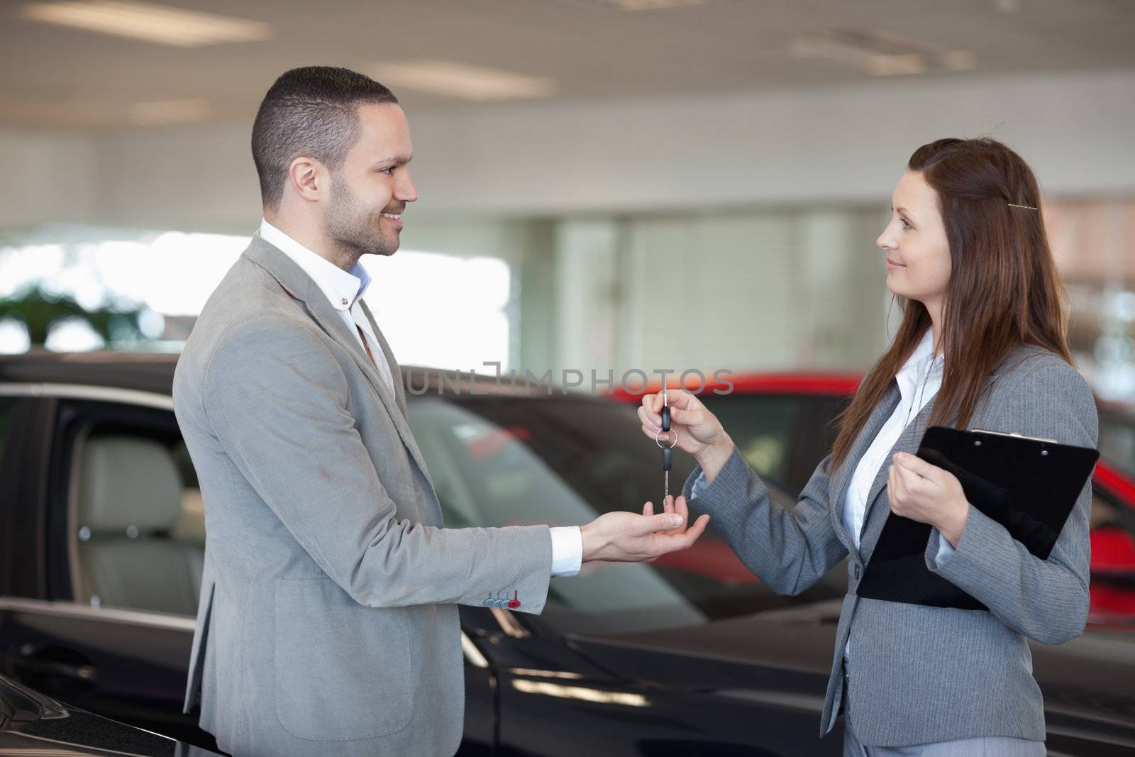 Woman giving car keys to a client in a dealership