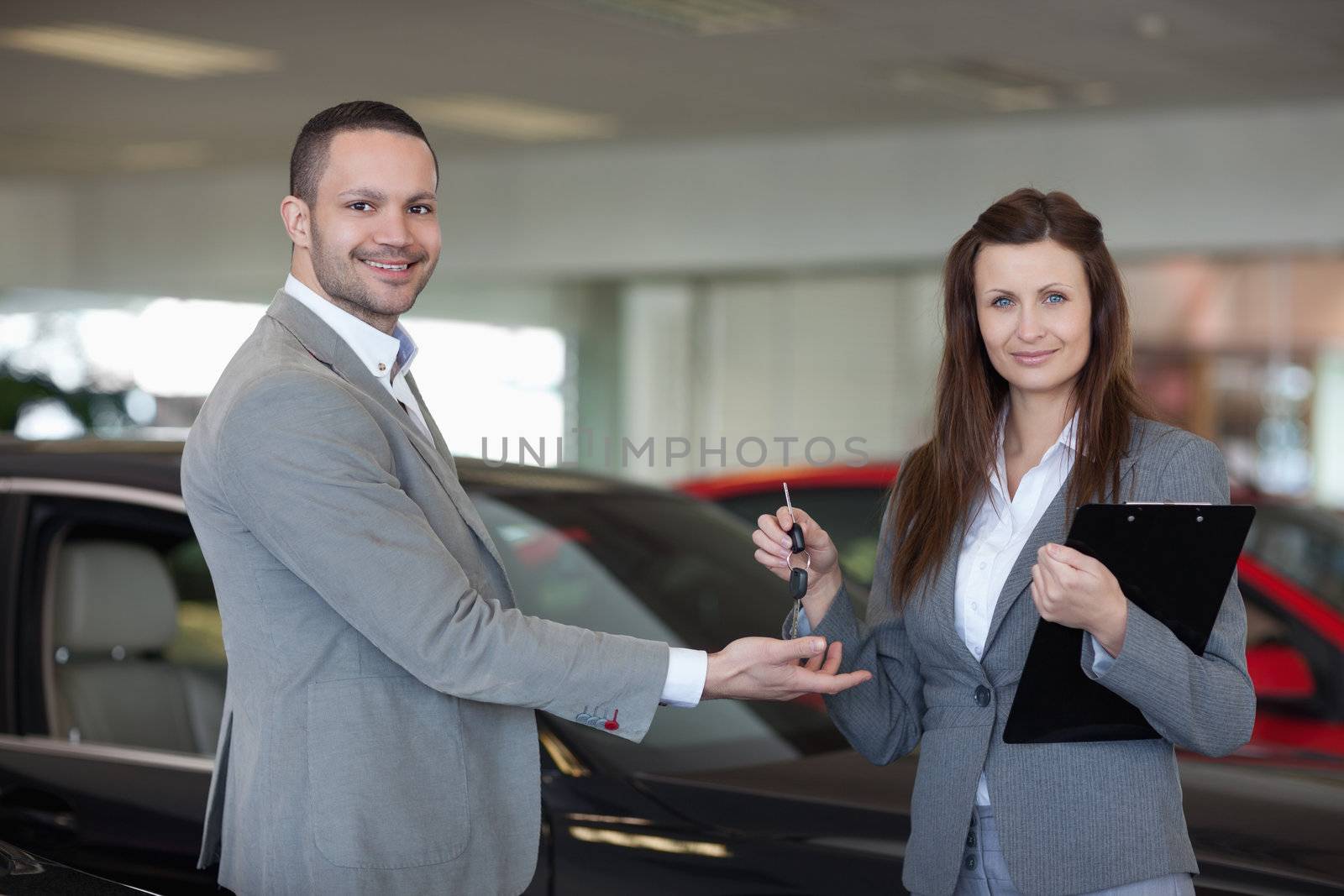 Woman giving car keys to a man in a dealership