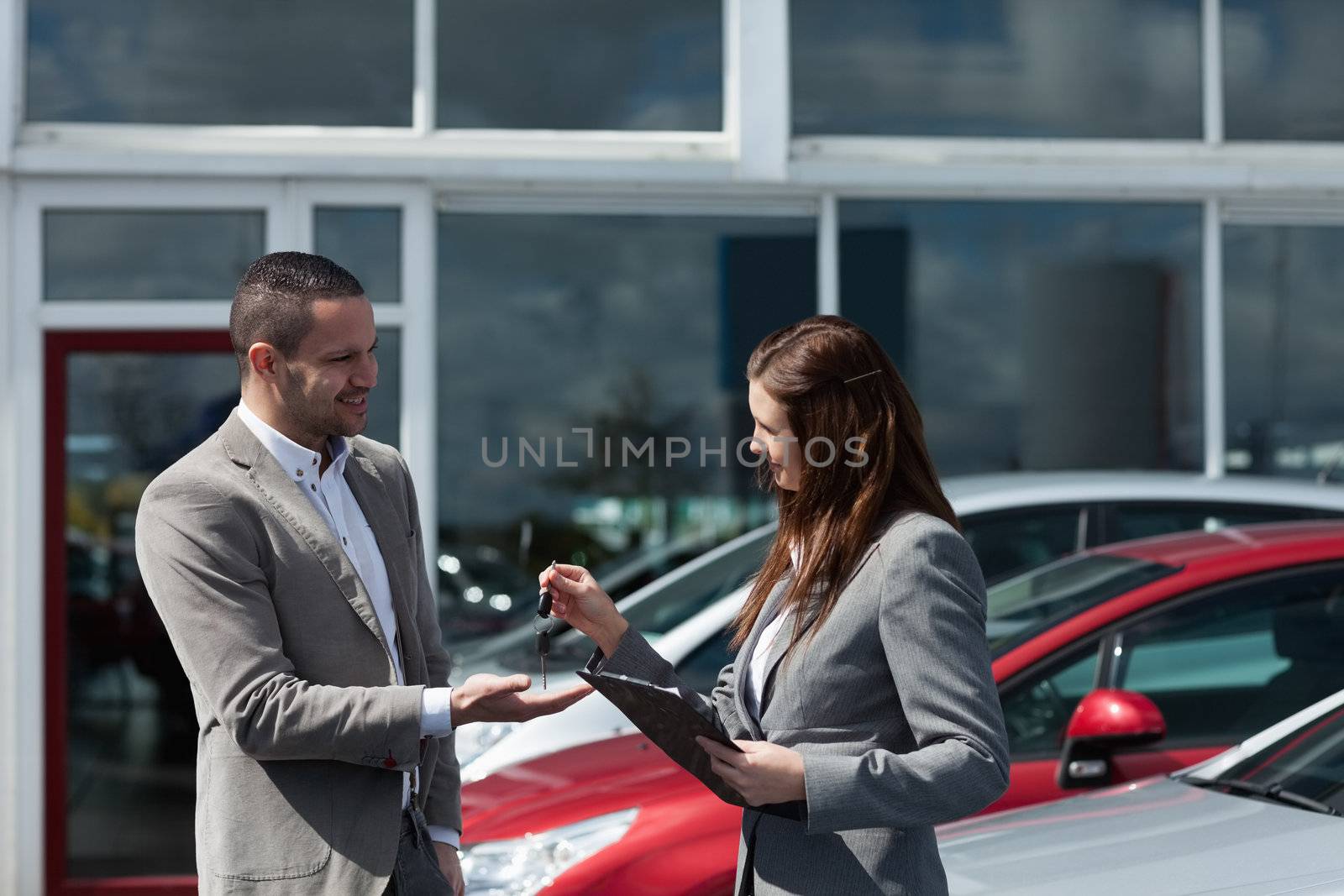 Businesswoman giving car keys to a client in a dealership