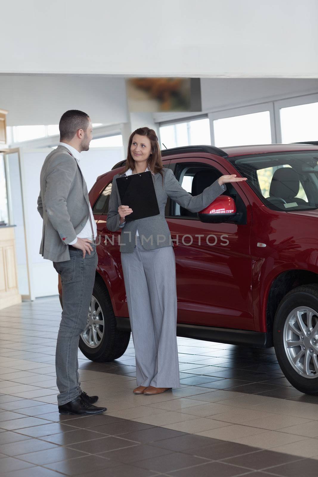 Businesswoman showing a car in a dealership
