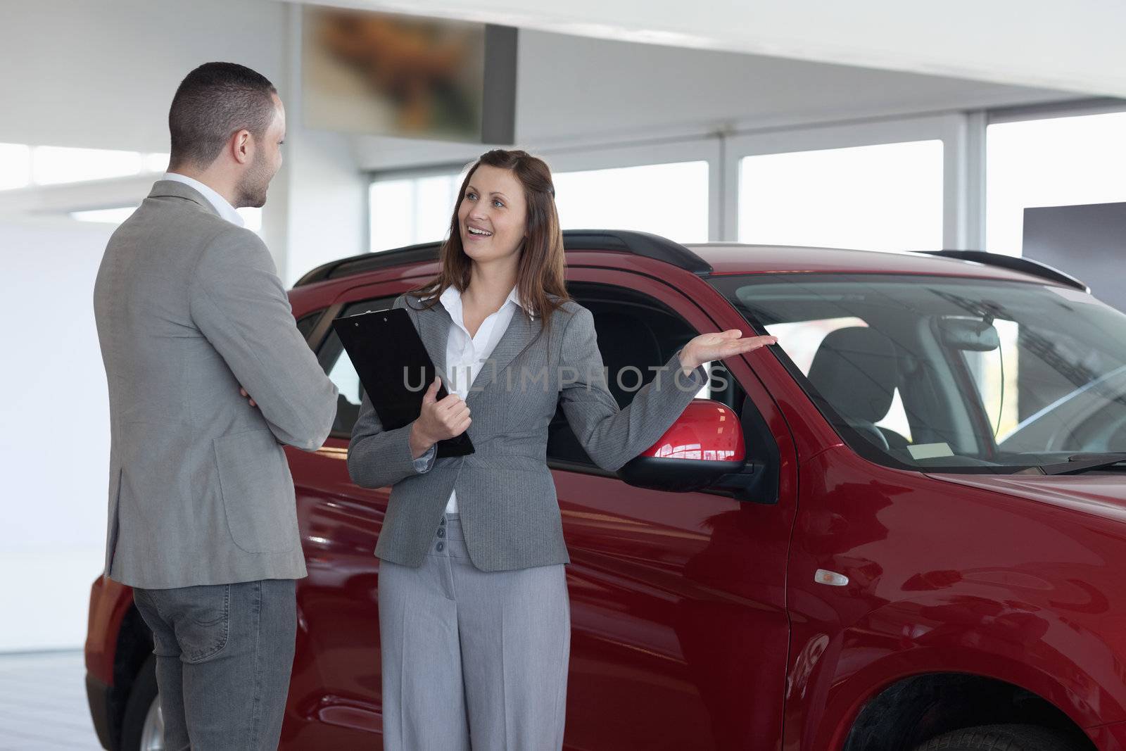 Businesswoman showing a car to a client in a dealership