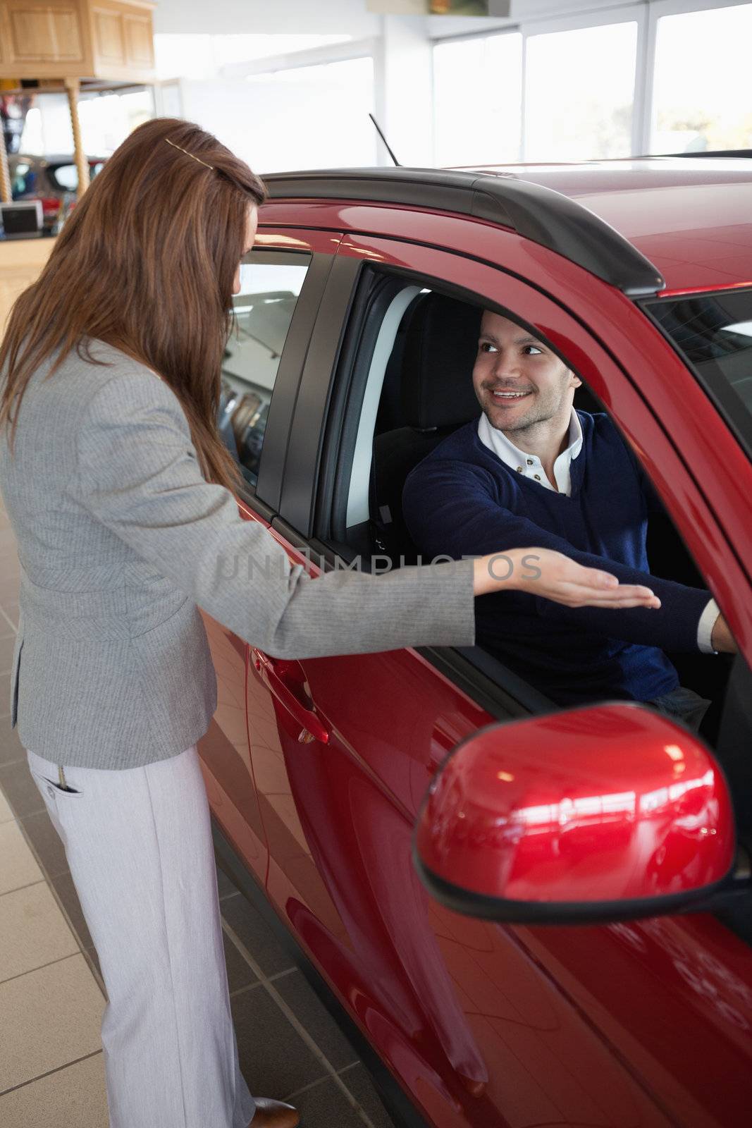 Businesswoman presenting the car to a client in a dealership