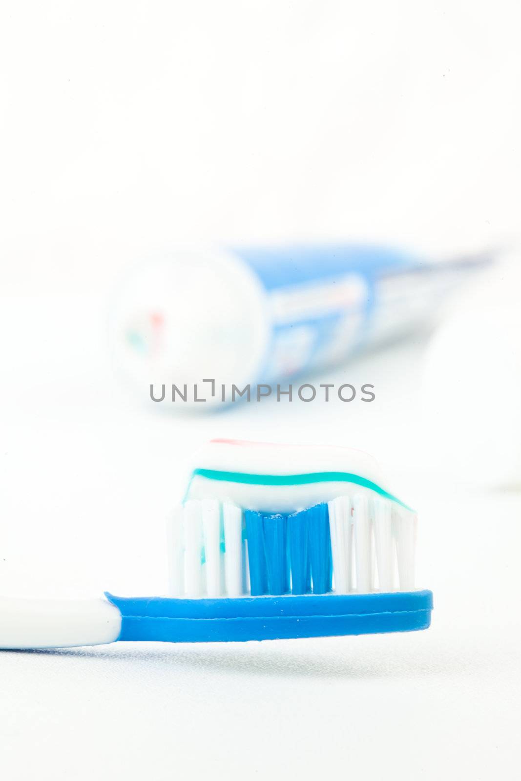 Tooth brush next to a tube of toothpaste by Wavebreakmedia